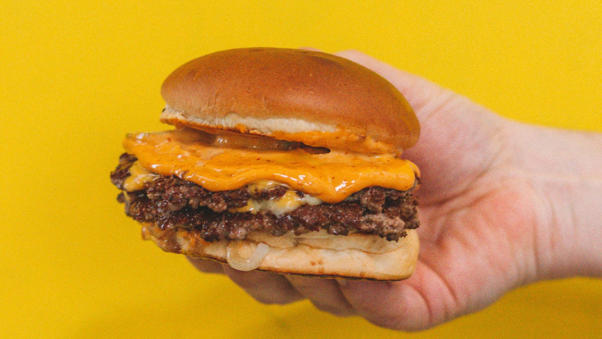 person holding burger with patty