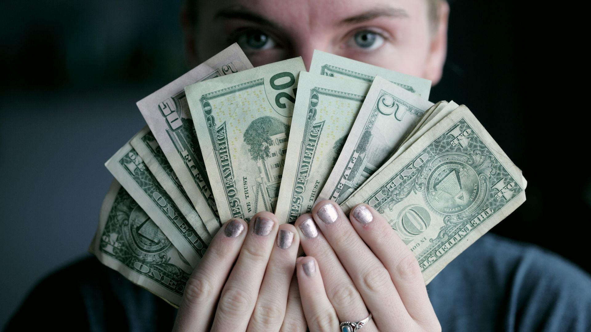 person holding fan of U.S. dollars banknote