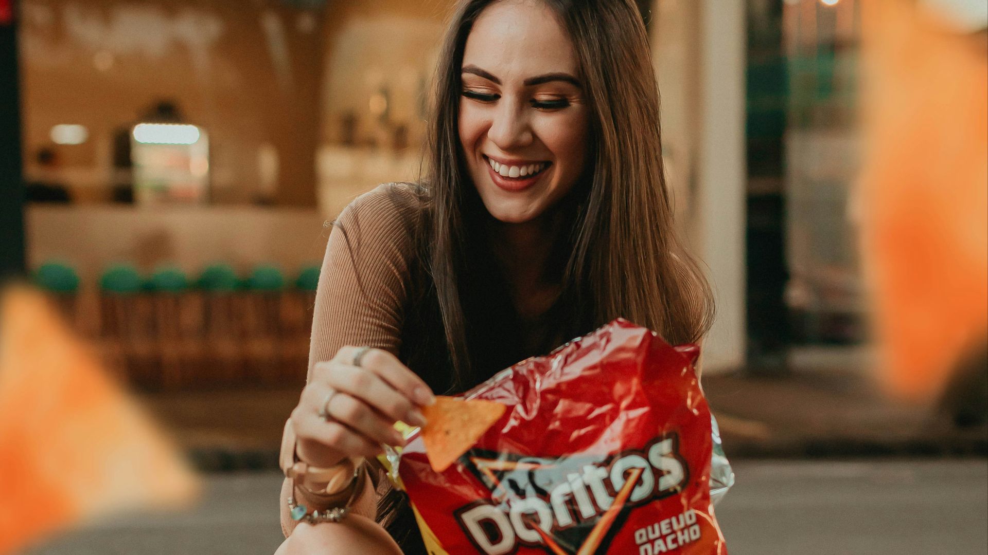 woman in black shirt sitting on the street holding red plastic pack
