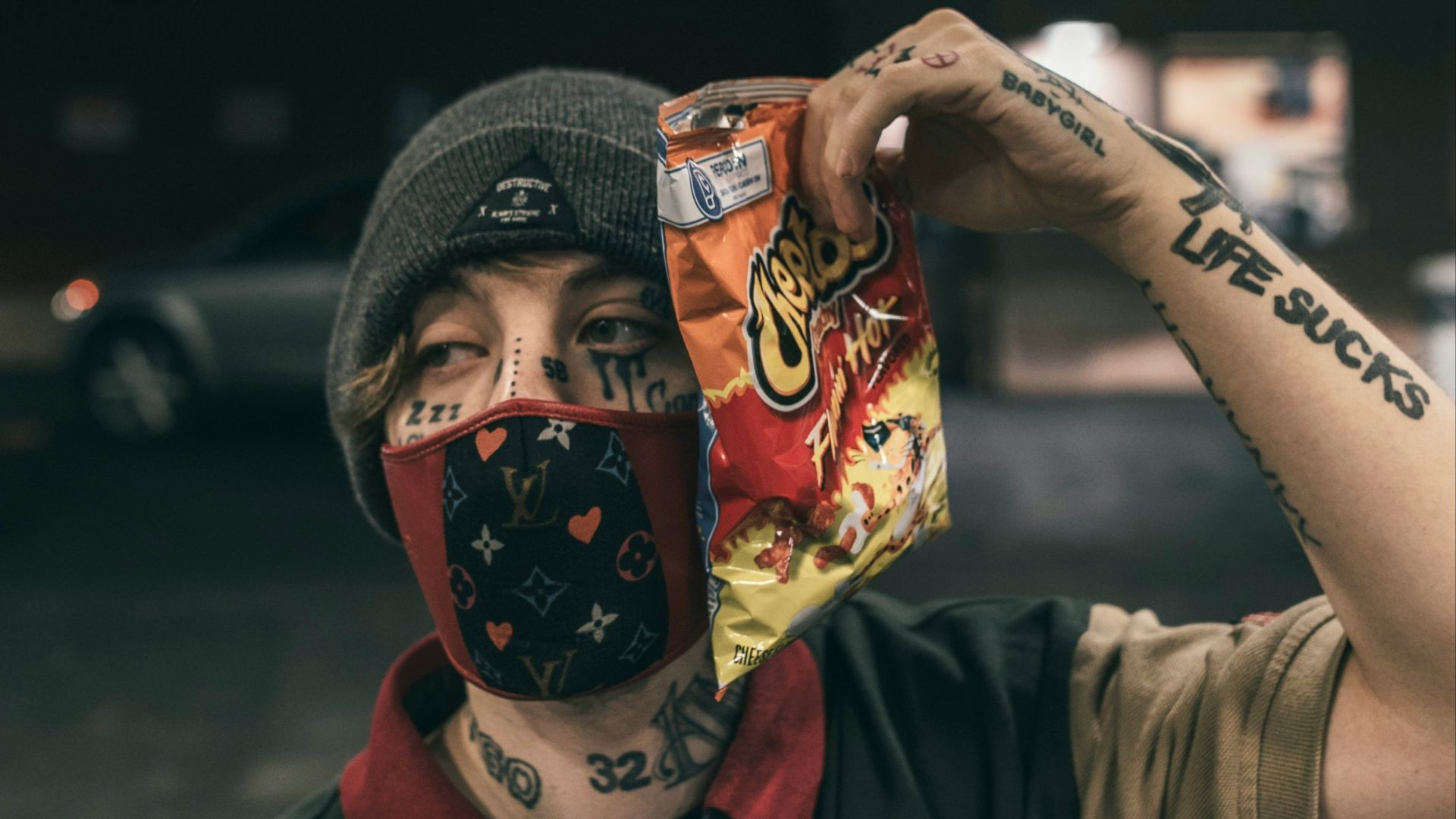 man in black button up shirt wearing black knit cap holding red and white mask