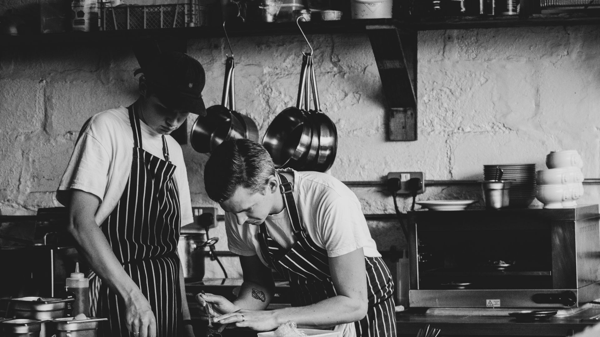 man in white crew neck t-shirt standing in front of kitchen sink