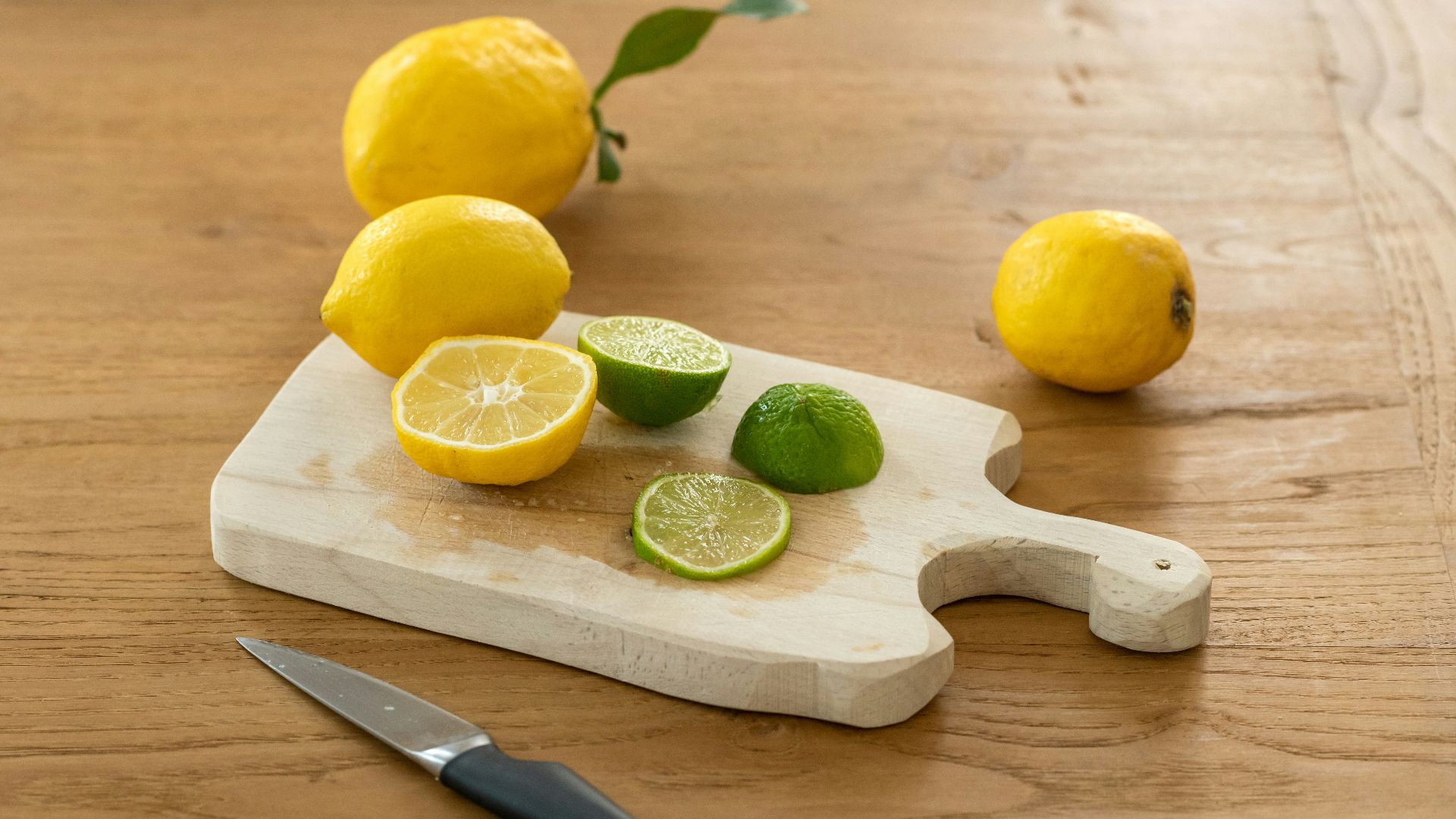 sliced lemon beside knife on brown wooden chopping board