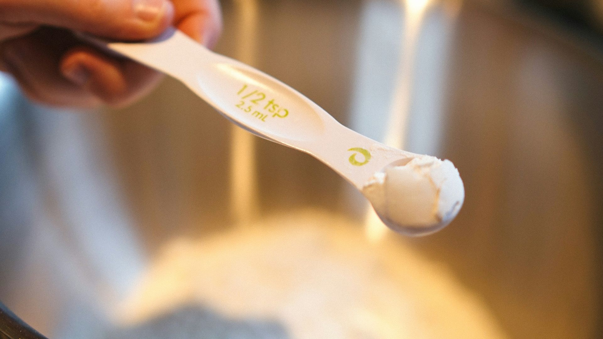 A person holding a toothbrush in a metal bowl
