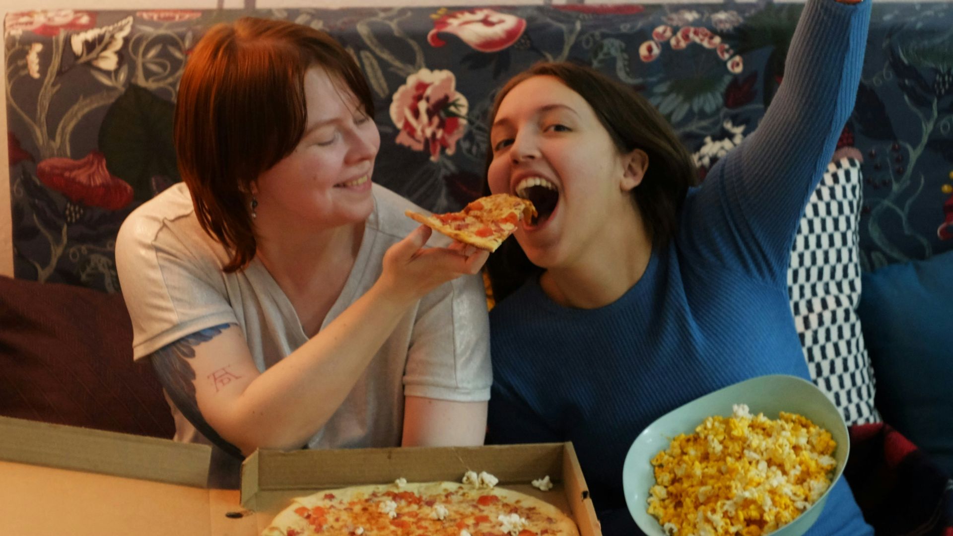 woman in white shirt eating pizza