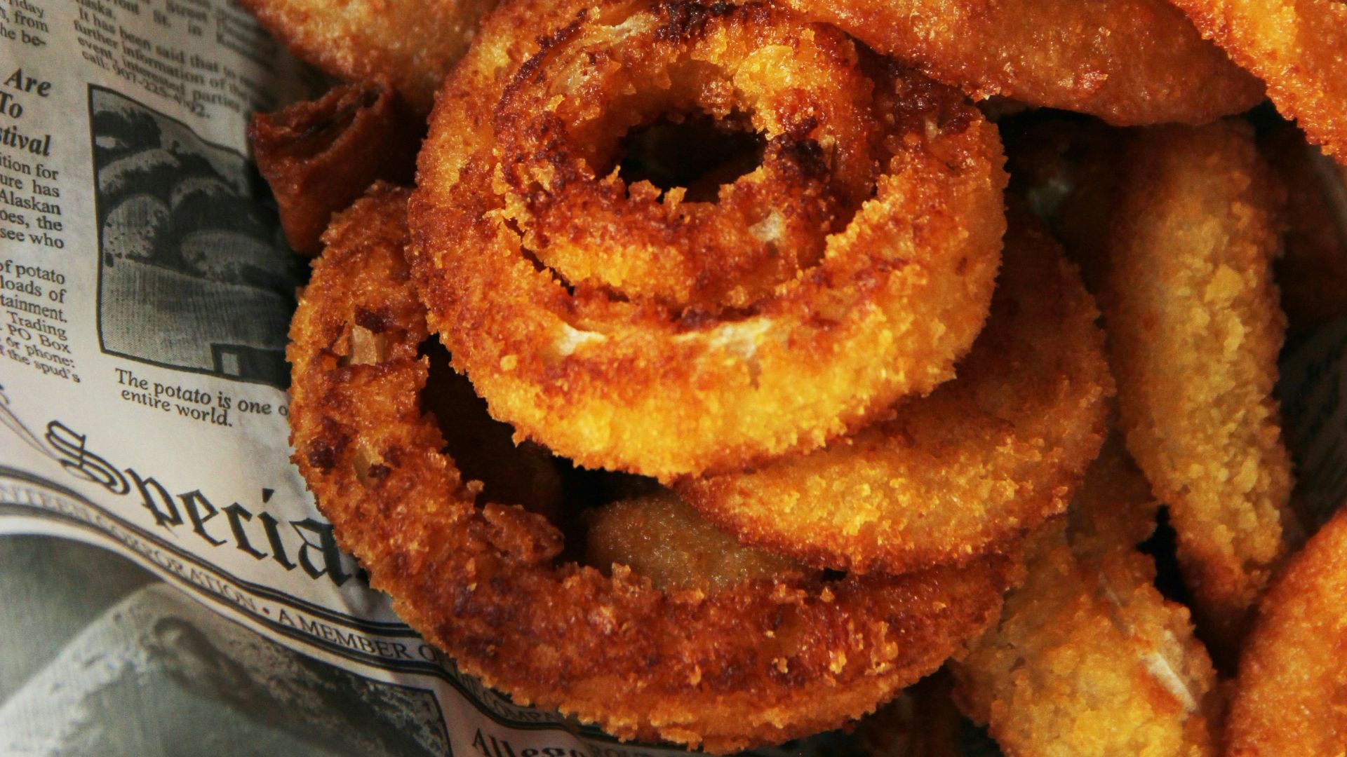 a pile of fried onion rings sitting on top of a newspaper