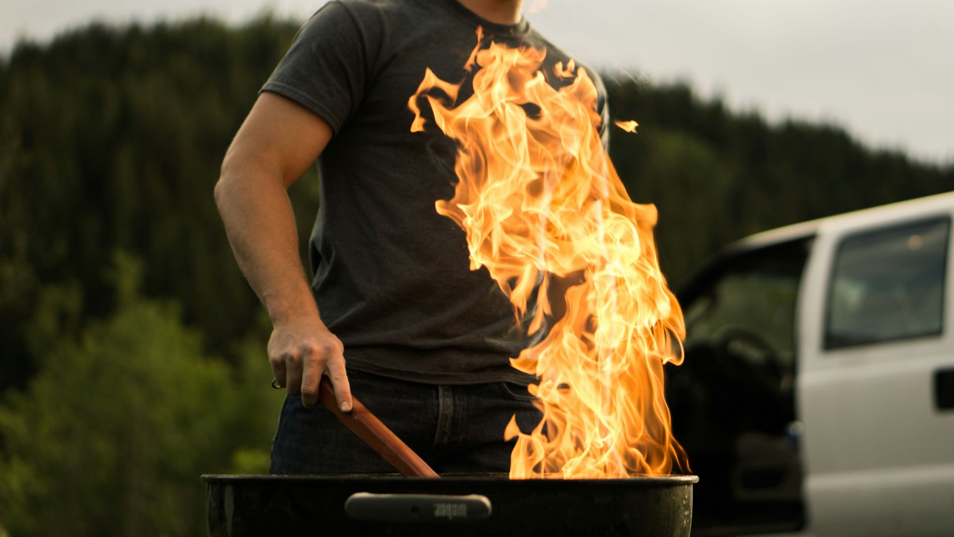 man grilling near white vehicle