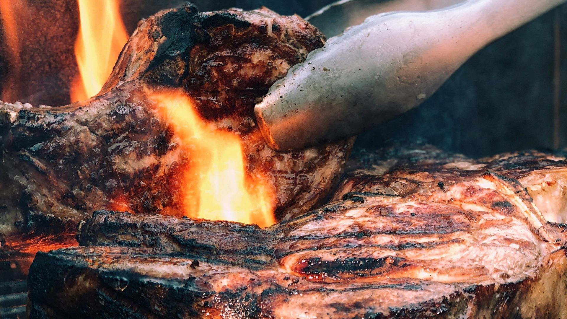 gray metal tong and grilled meat with fire