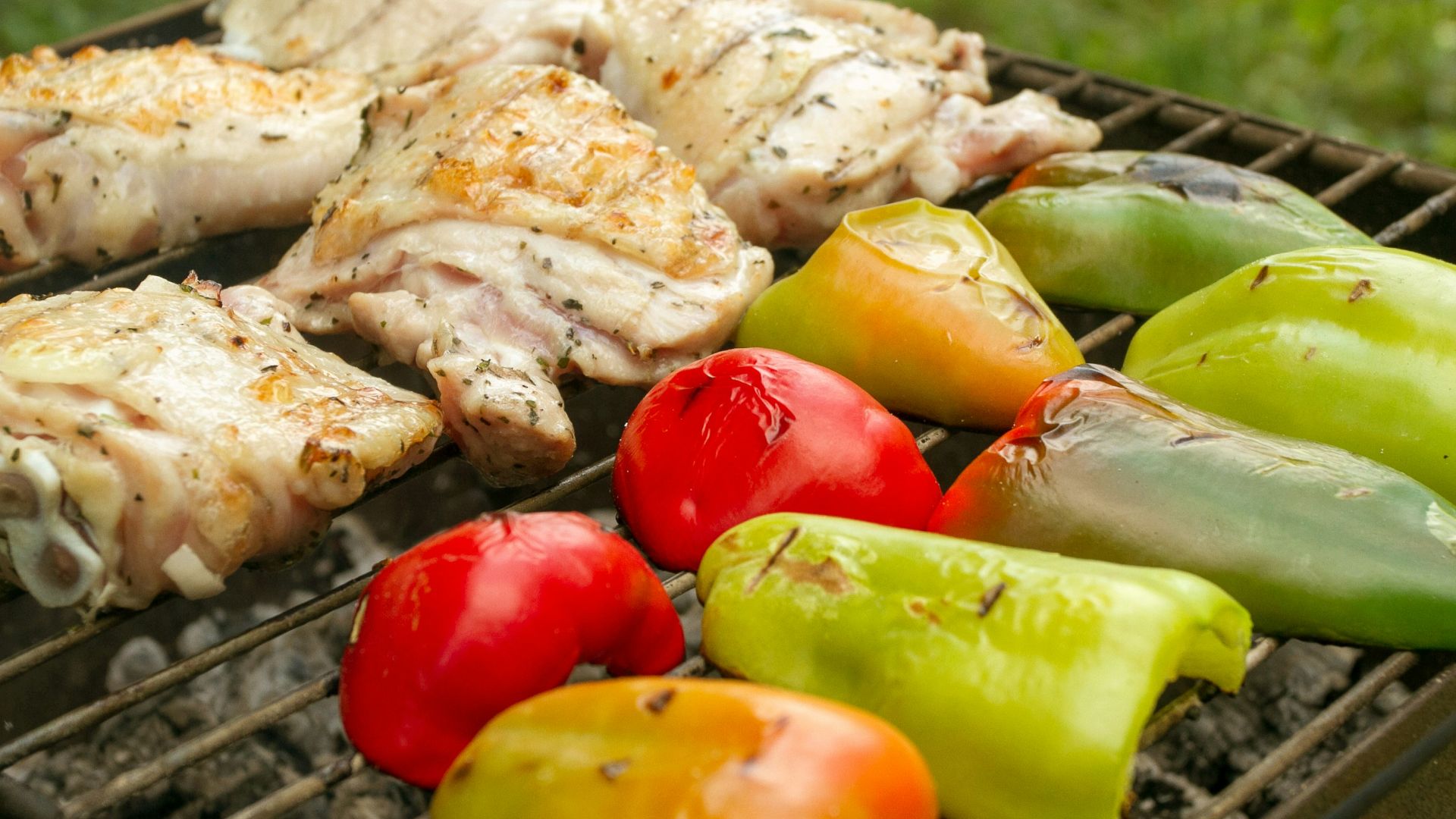 a bbq with chicken, peppers, and peppers on it