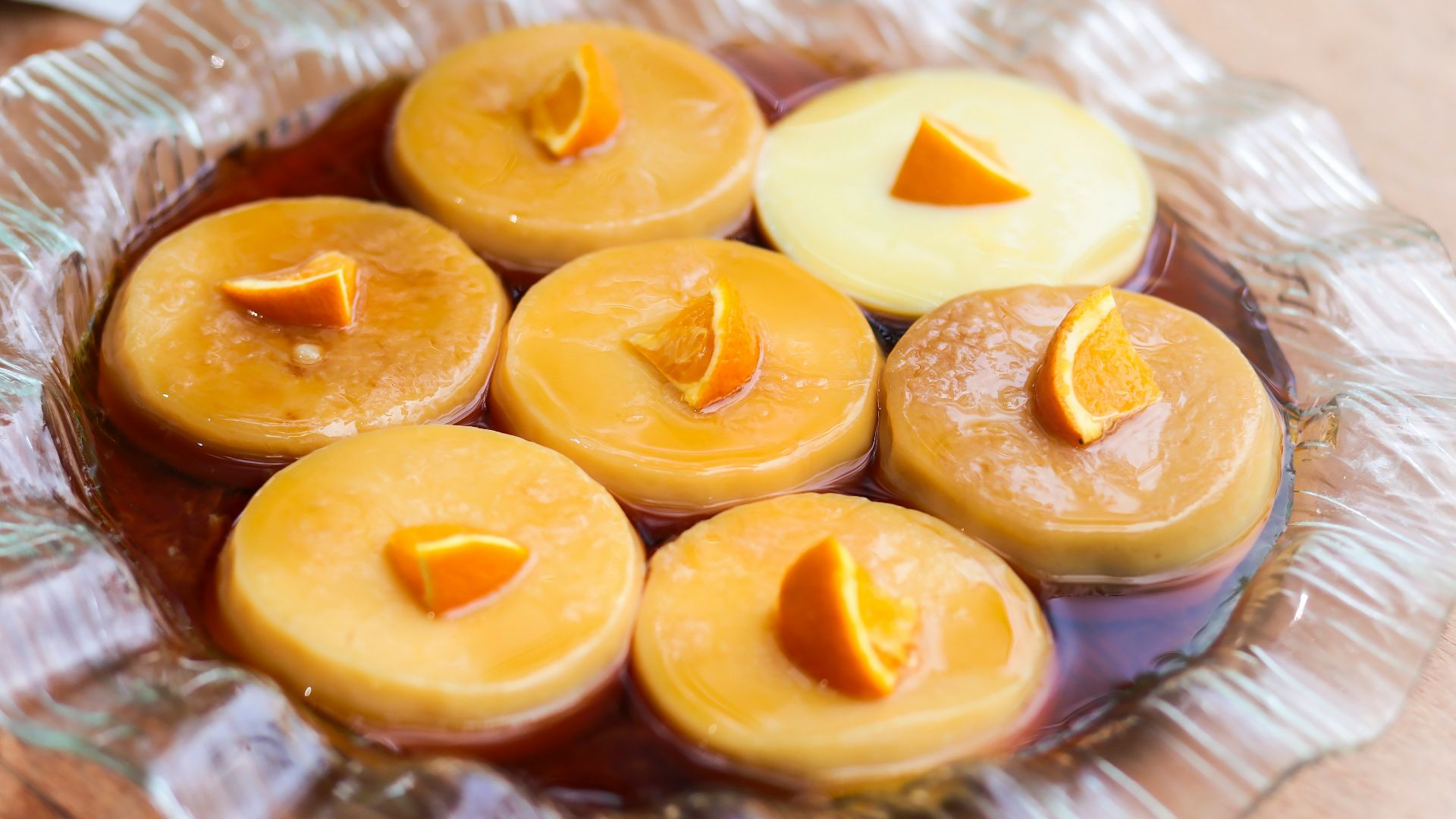 a glass bowl filled with yellow candles on top of a wooden table