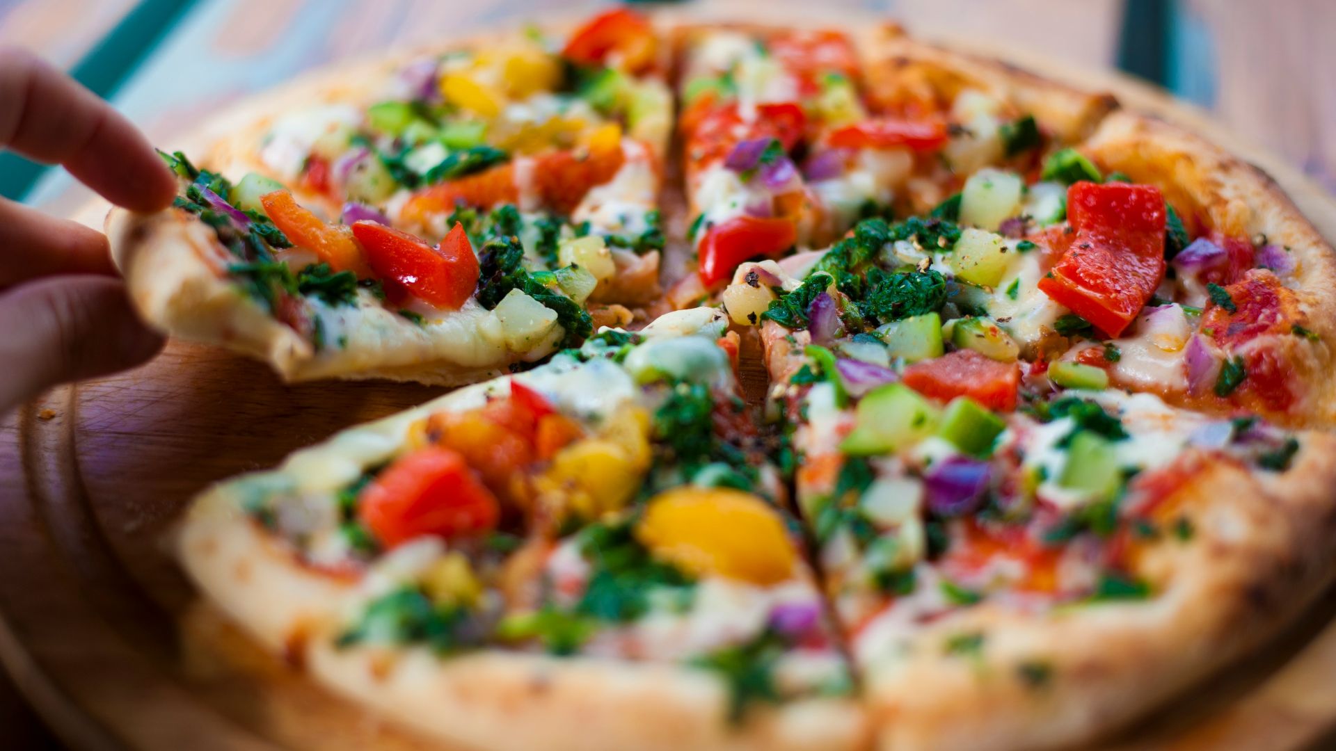 pizza with green and red bell pepper and cheese on brown wooden table