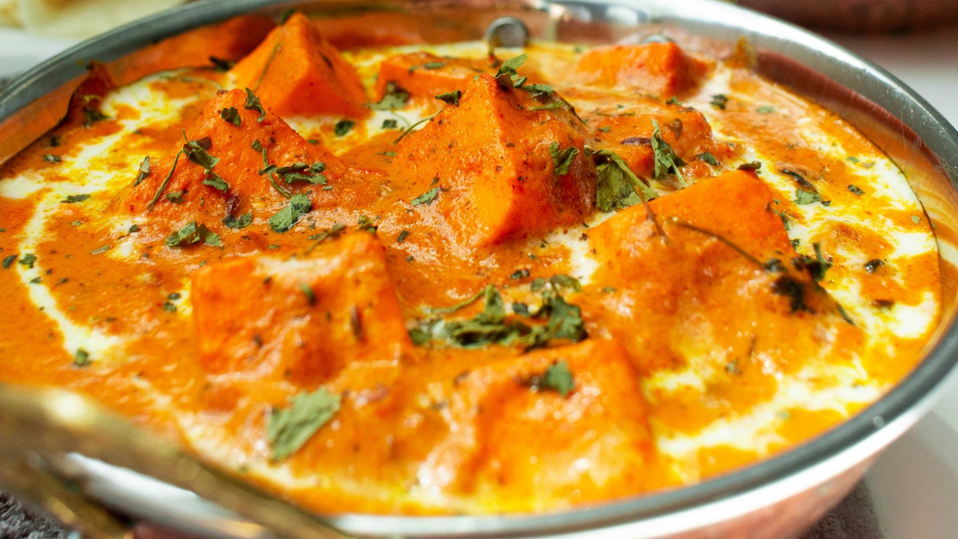 a metal bowl filled with food next to a bowl of rice