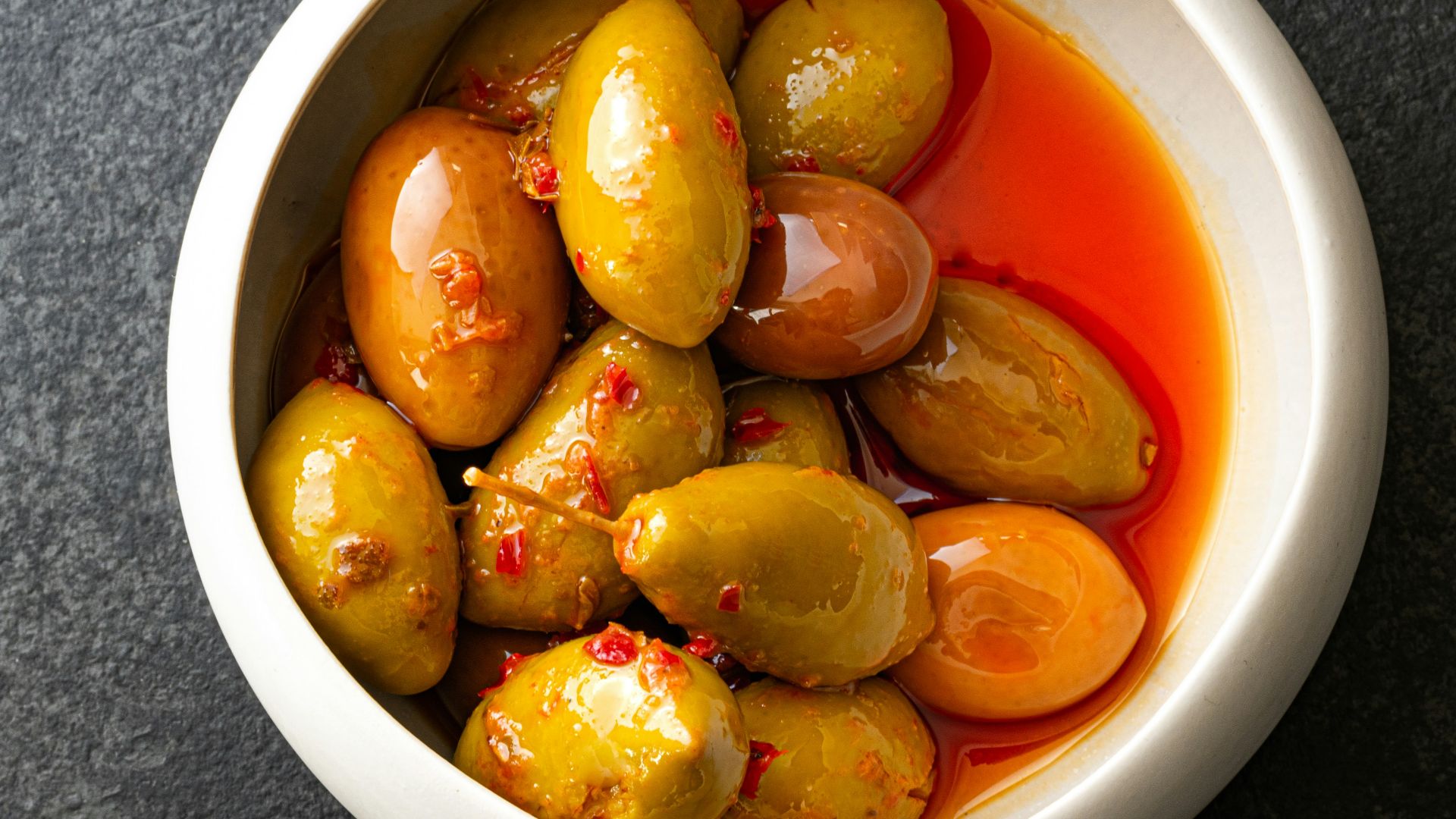 a white bowl filled with olives and tomatoes