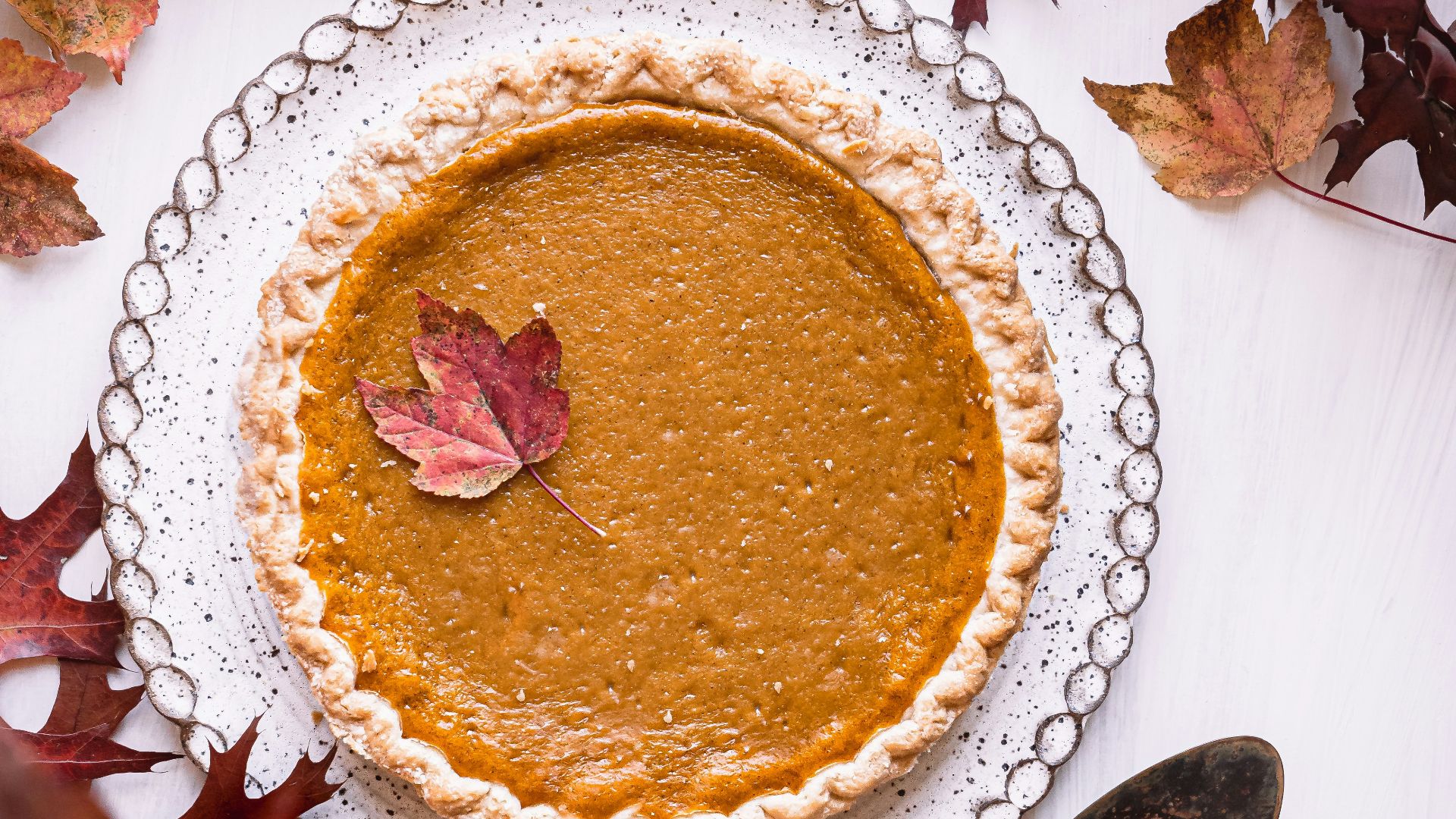 a pie sitting on top of a white table next to leaves