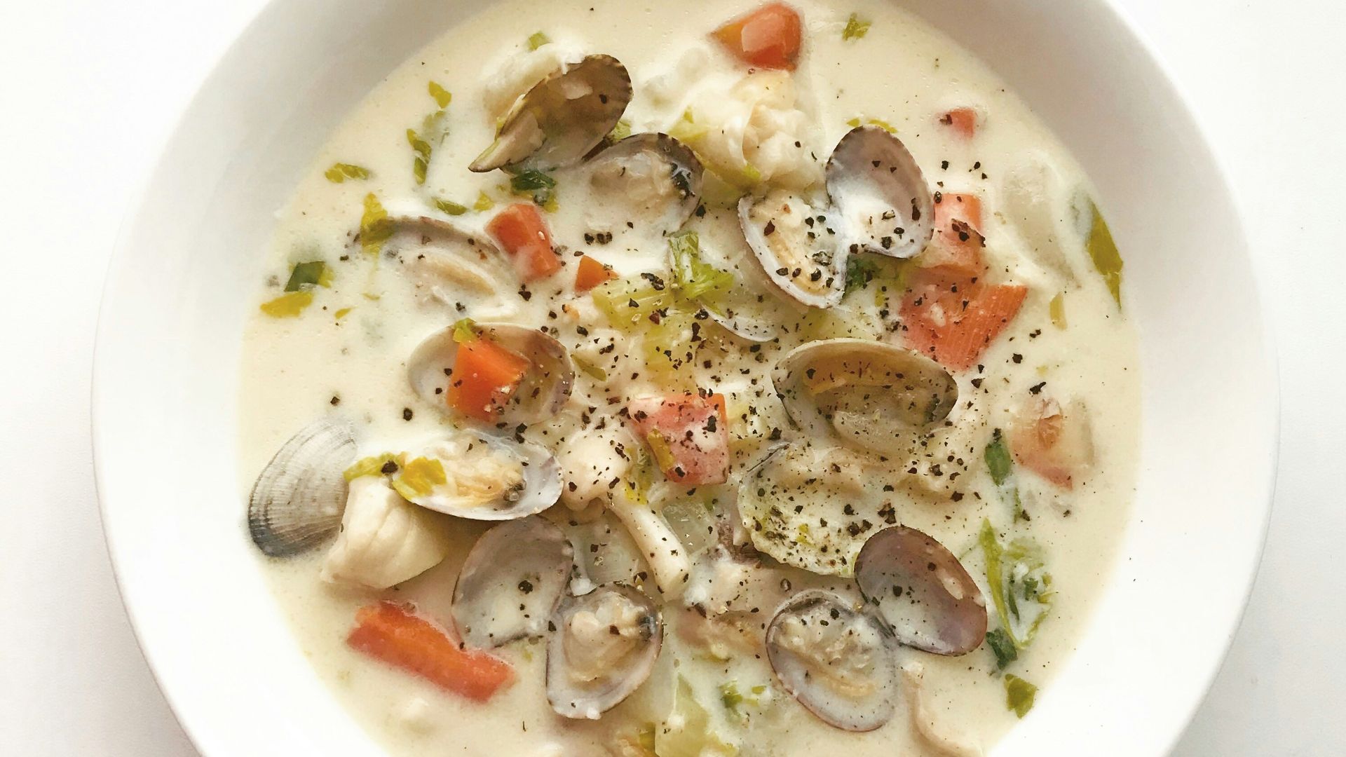 clam and vegetable soup in white ceramic bowl