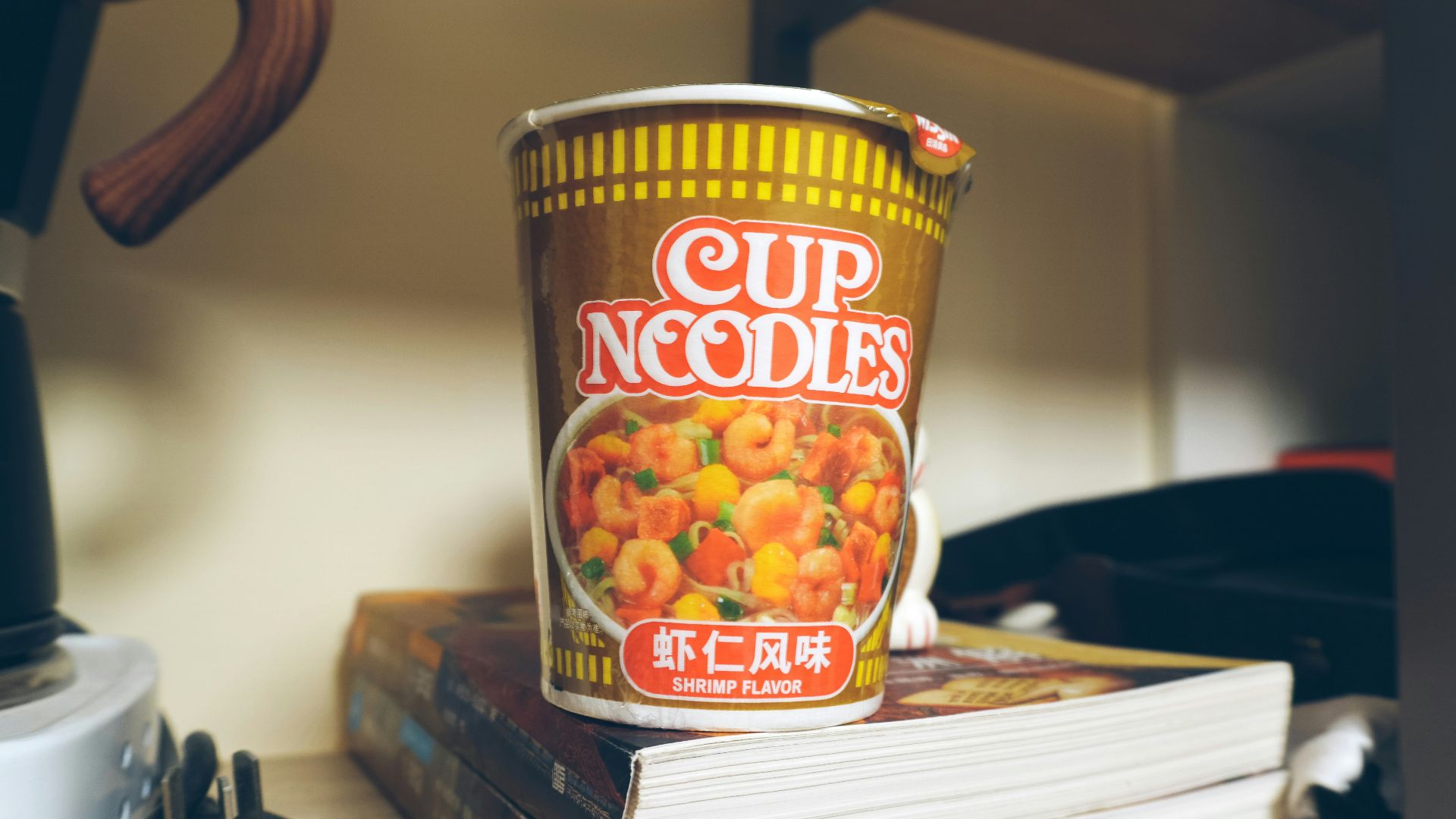 a cup of noodles sitting on top of a stack of books