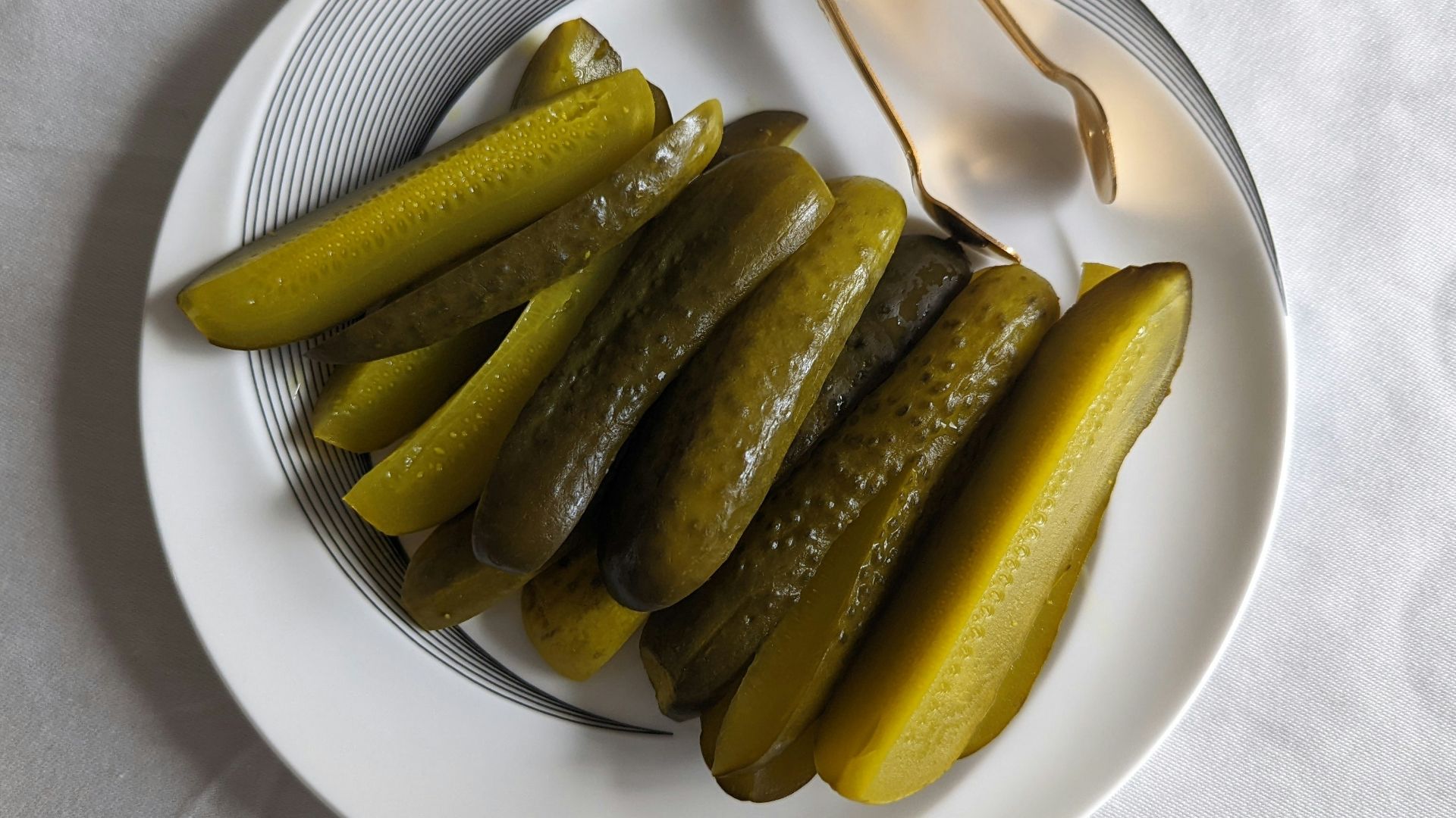 a white plate topped with pickles next to a fork