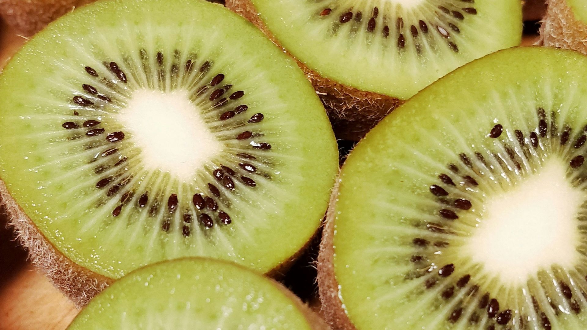 a bunch of kiwi cut in half on a cutting board