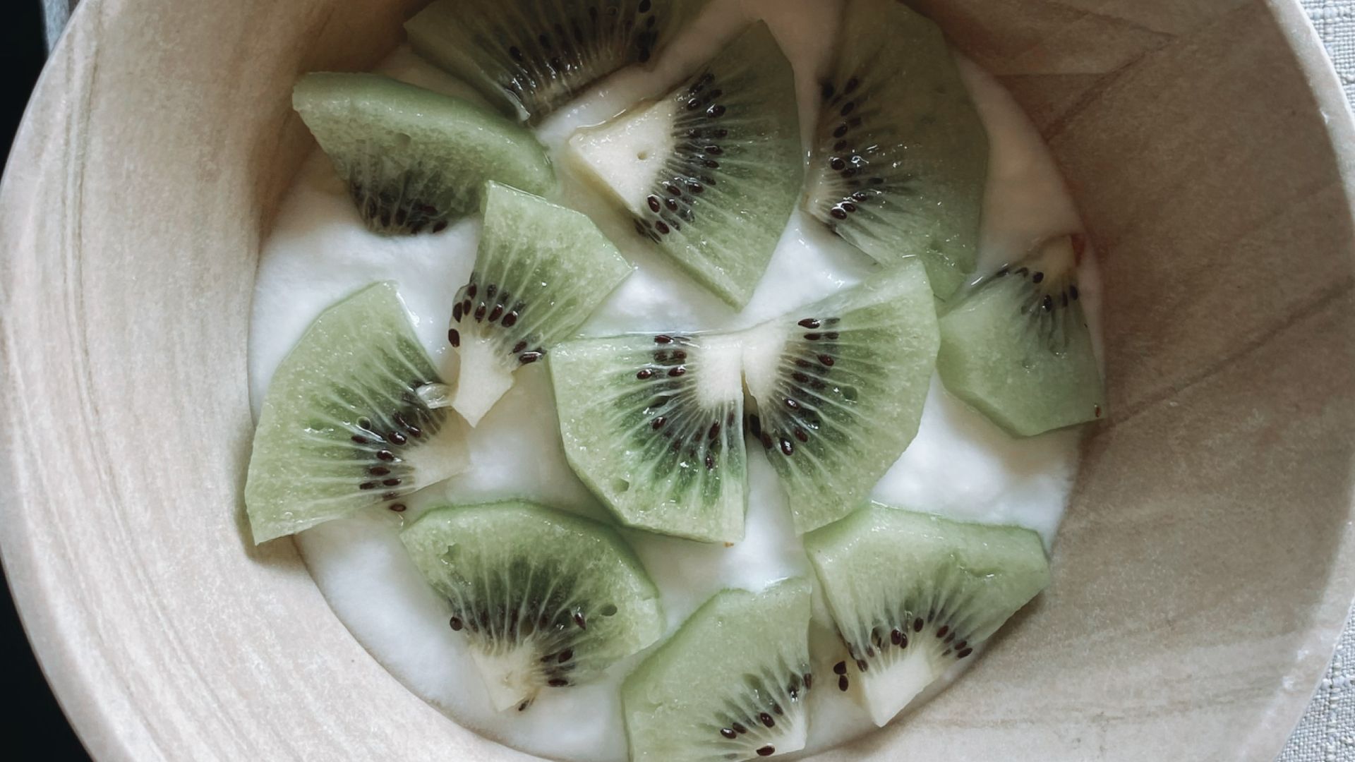 sliced kiwi fruit in brown wooden bowl