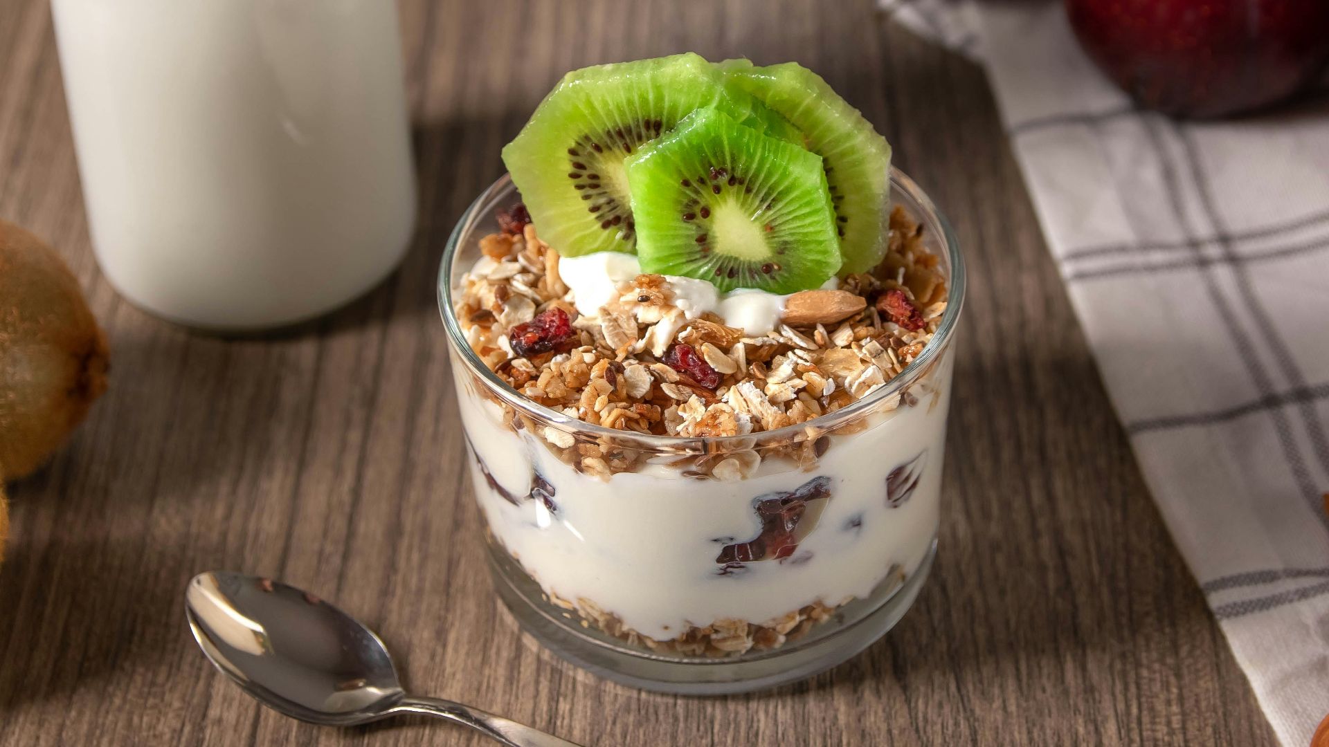 strawberry and green fruit on white ceramic bowl beside stainless steel spoon