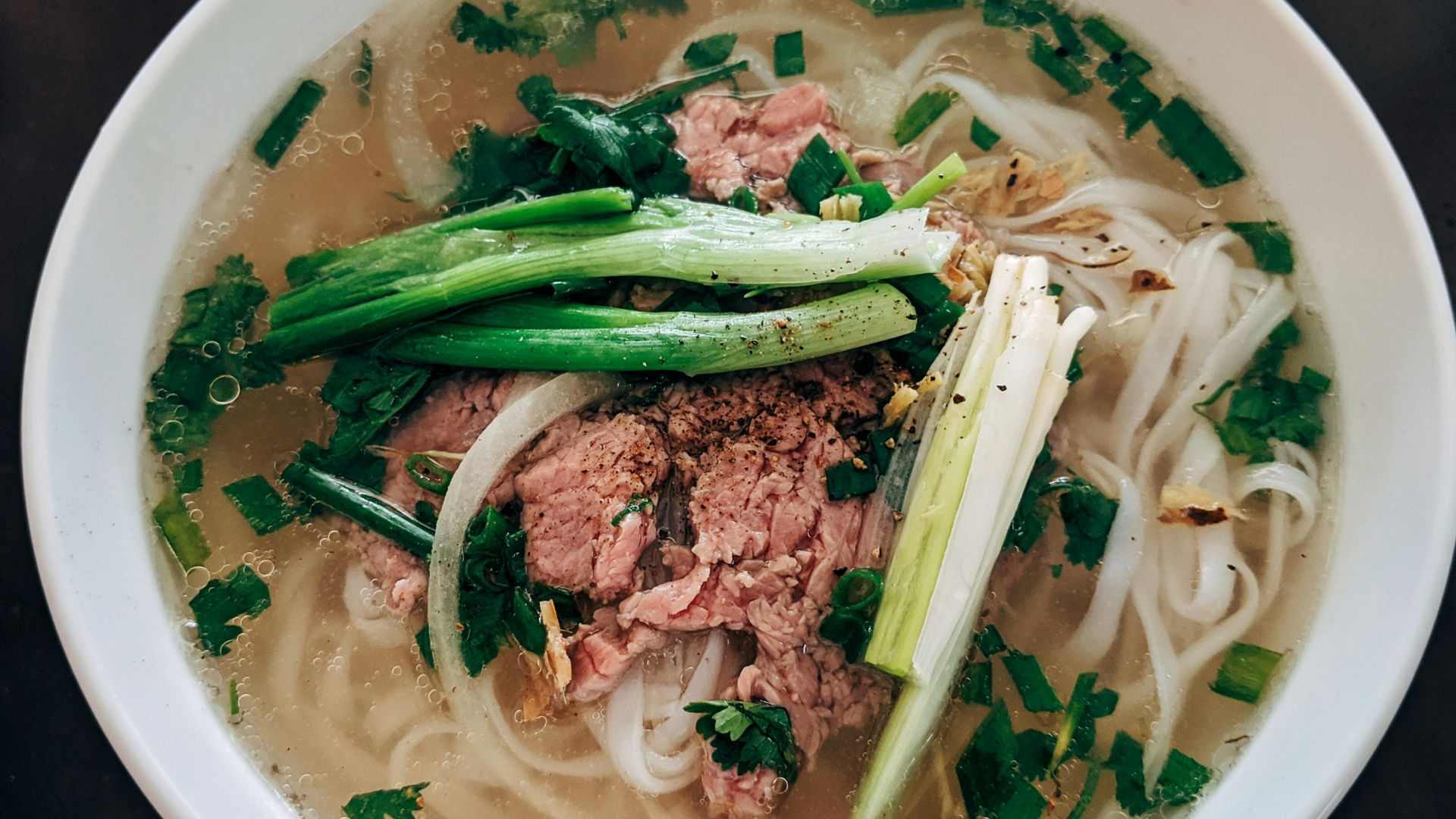 white noodle soup with green leaf vegetable in white ceramic bowl