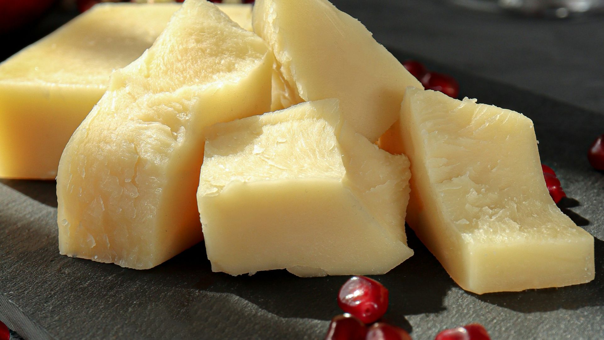 sliced cheese on black plate beside wine glass