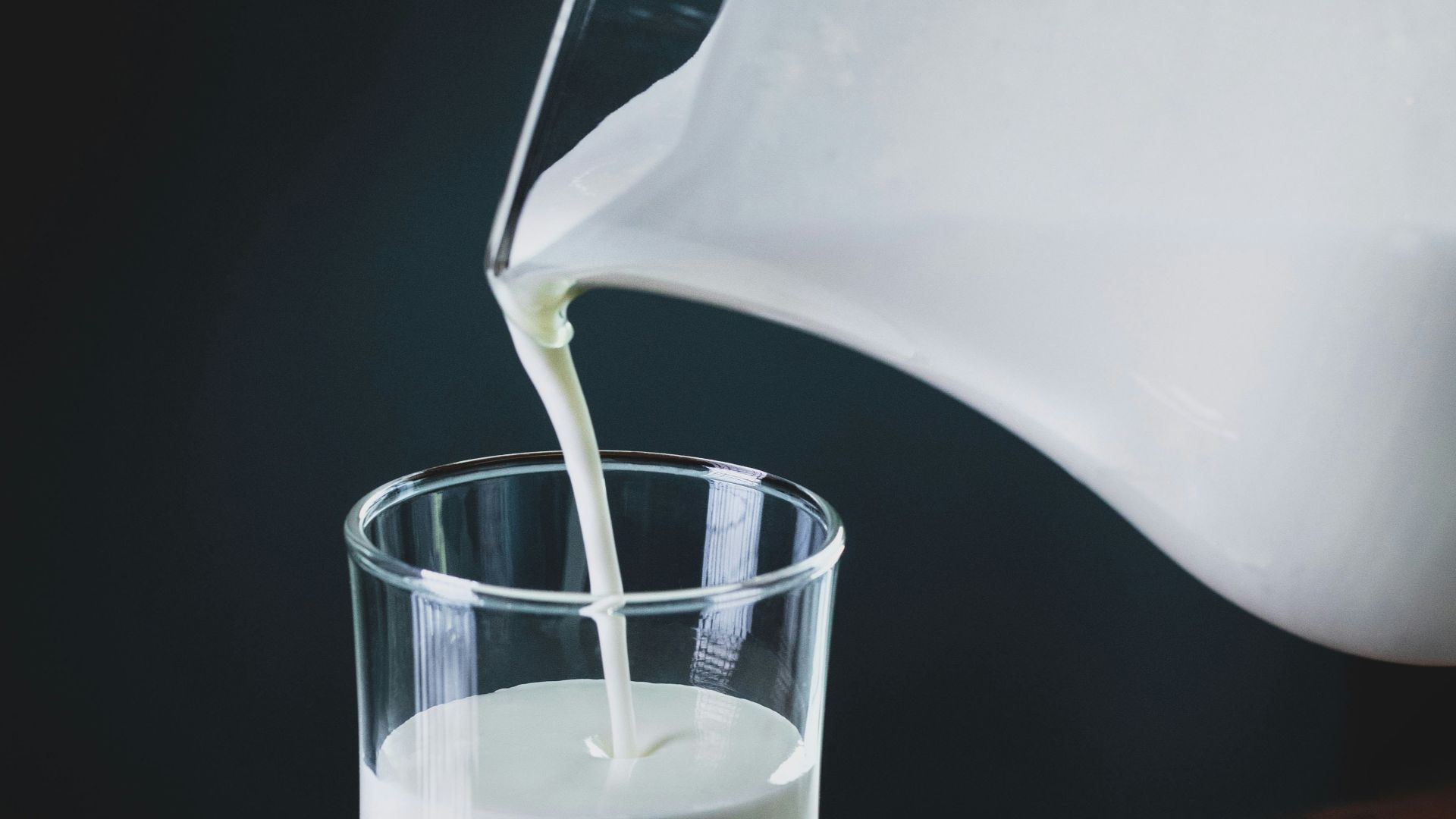 person pours milk into glass
