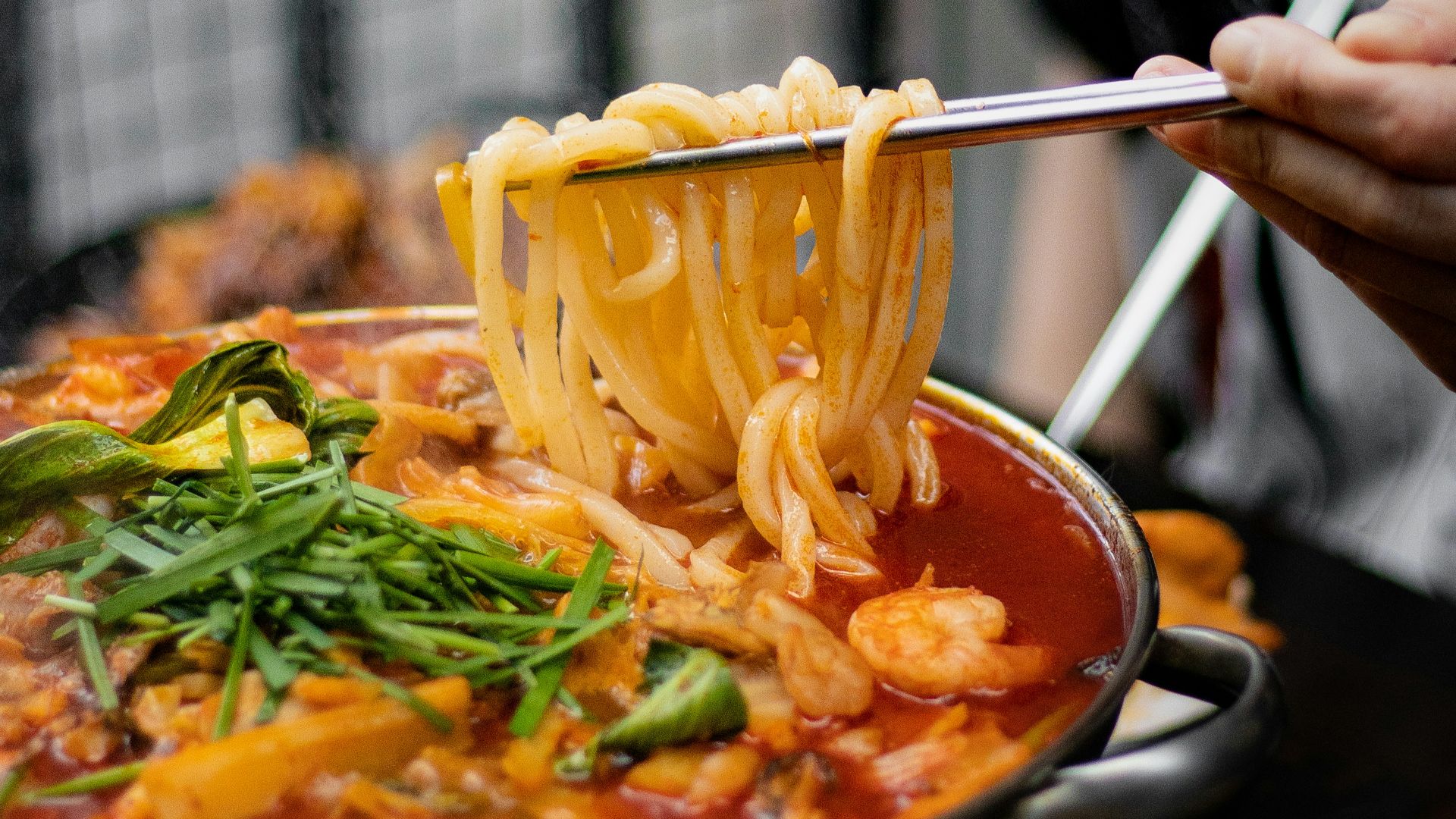 a person holding a spoon full of noodles