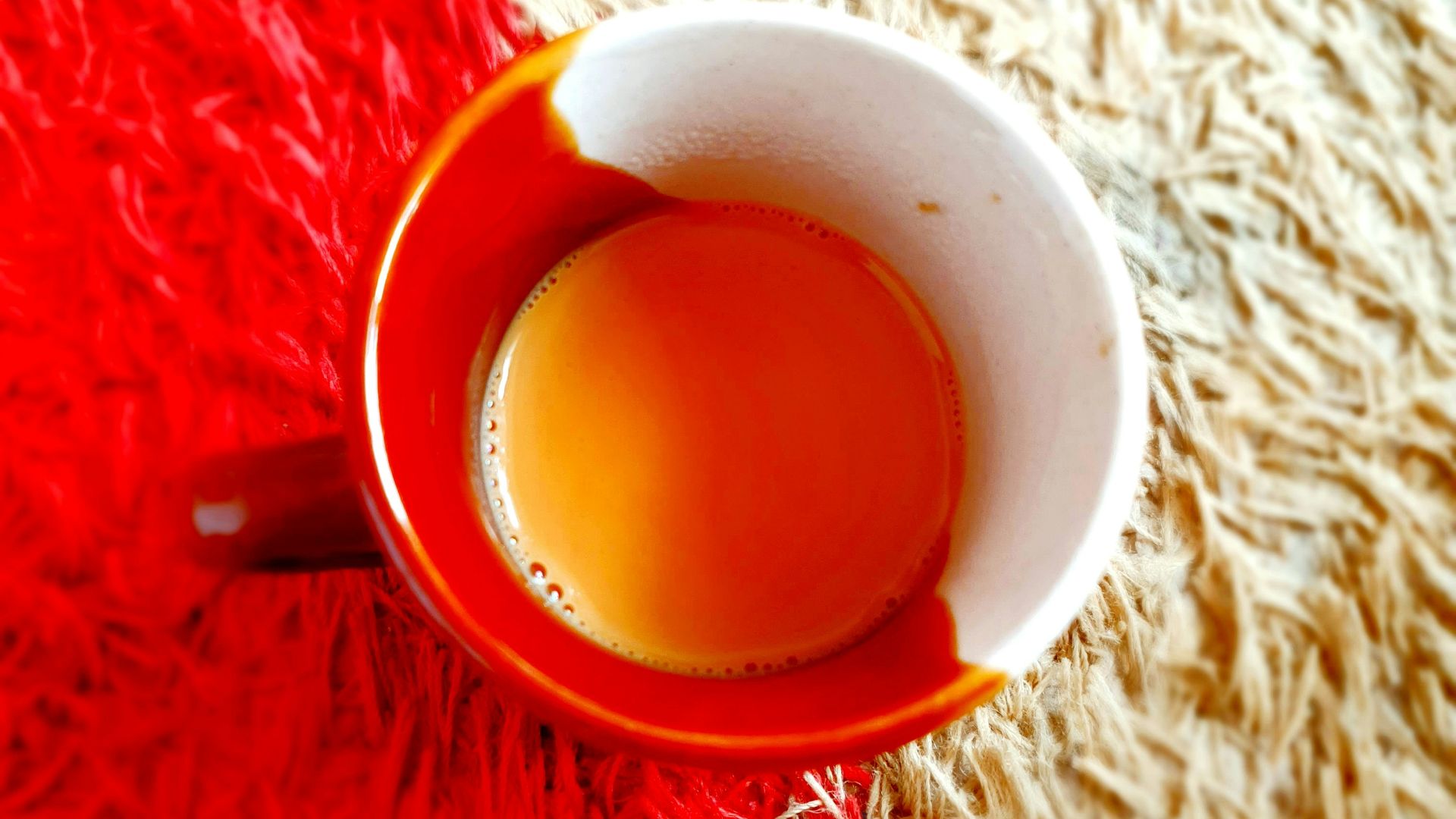 red and white ceramic mug on red textile