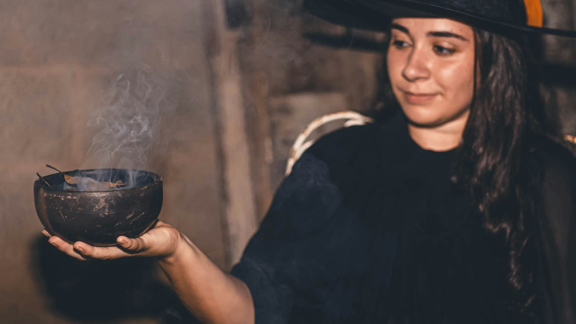 a woman in a witches costume holding a bowl