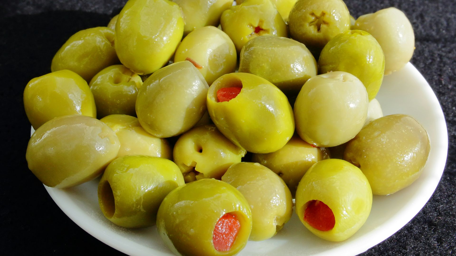 a white plate filled with green olives on a table