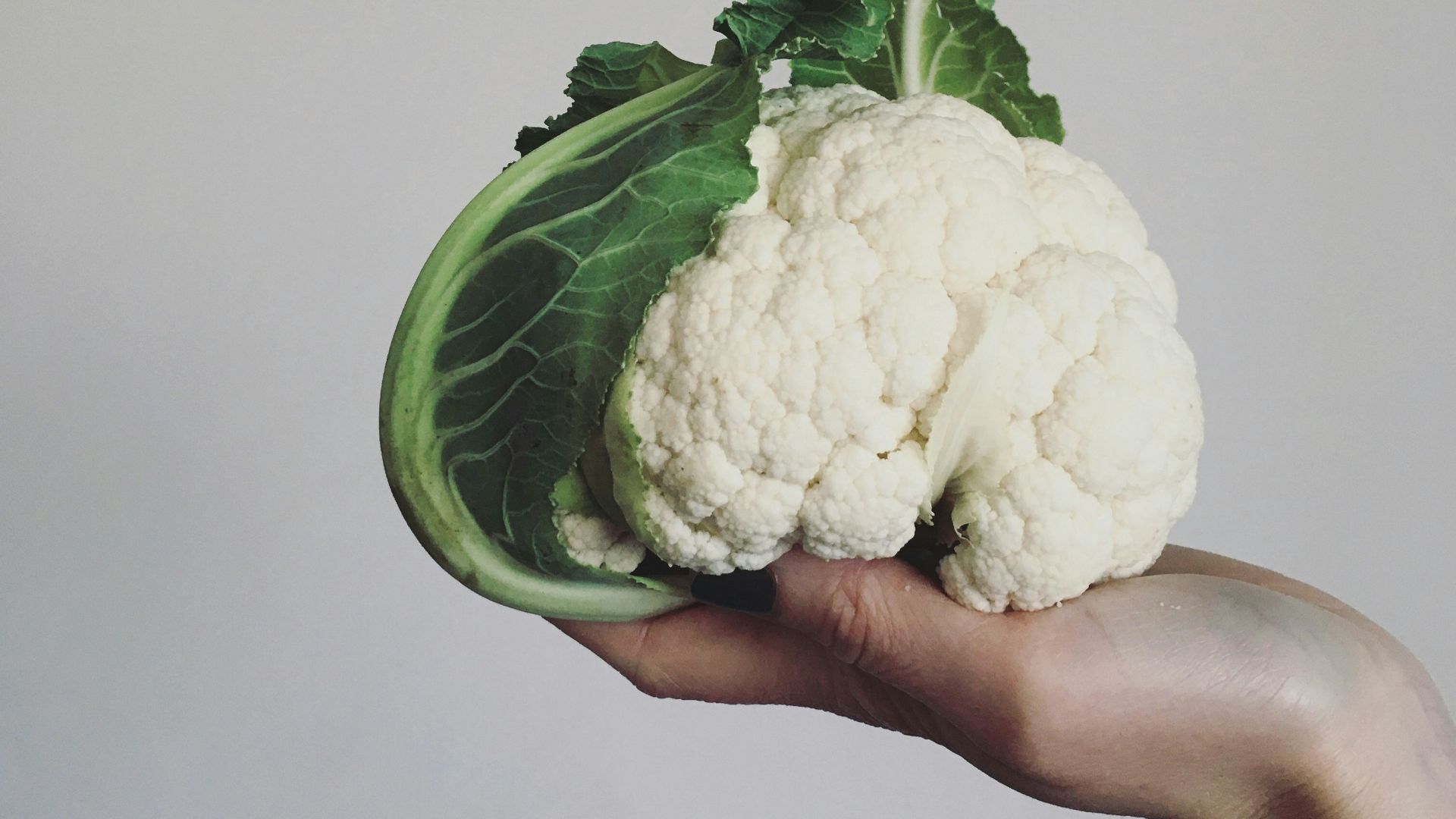 a person holding a piece of cauliflower in their hand
