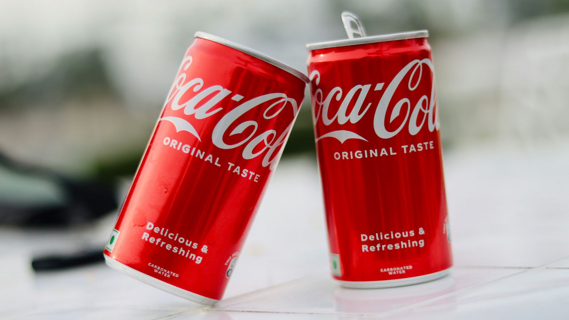 two cans of coca cola sitting on a table
