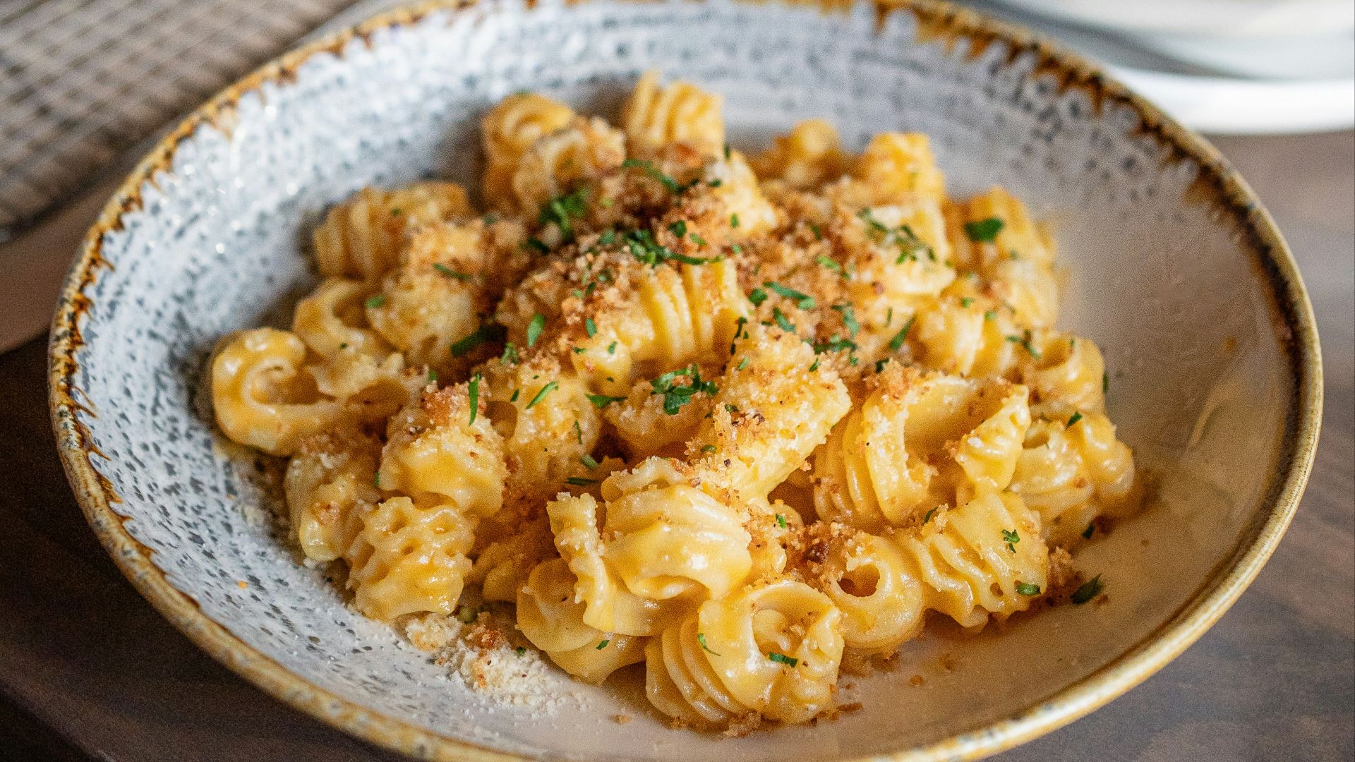 a bowl of pasta and a plate of pizza on a table