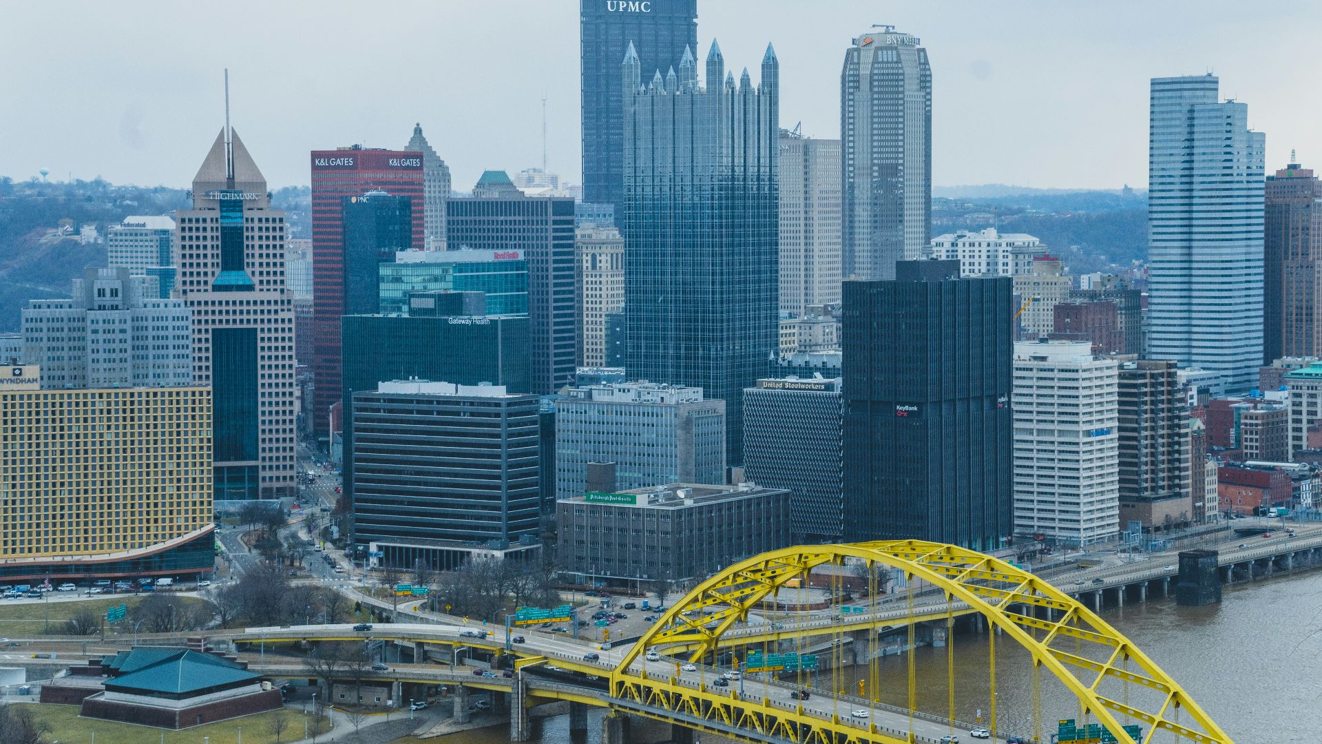 a yellow bridge over a river in front of a city