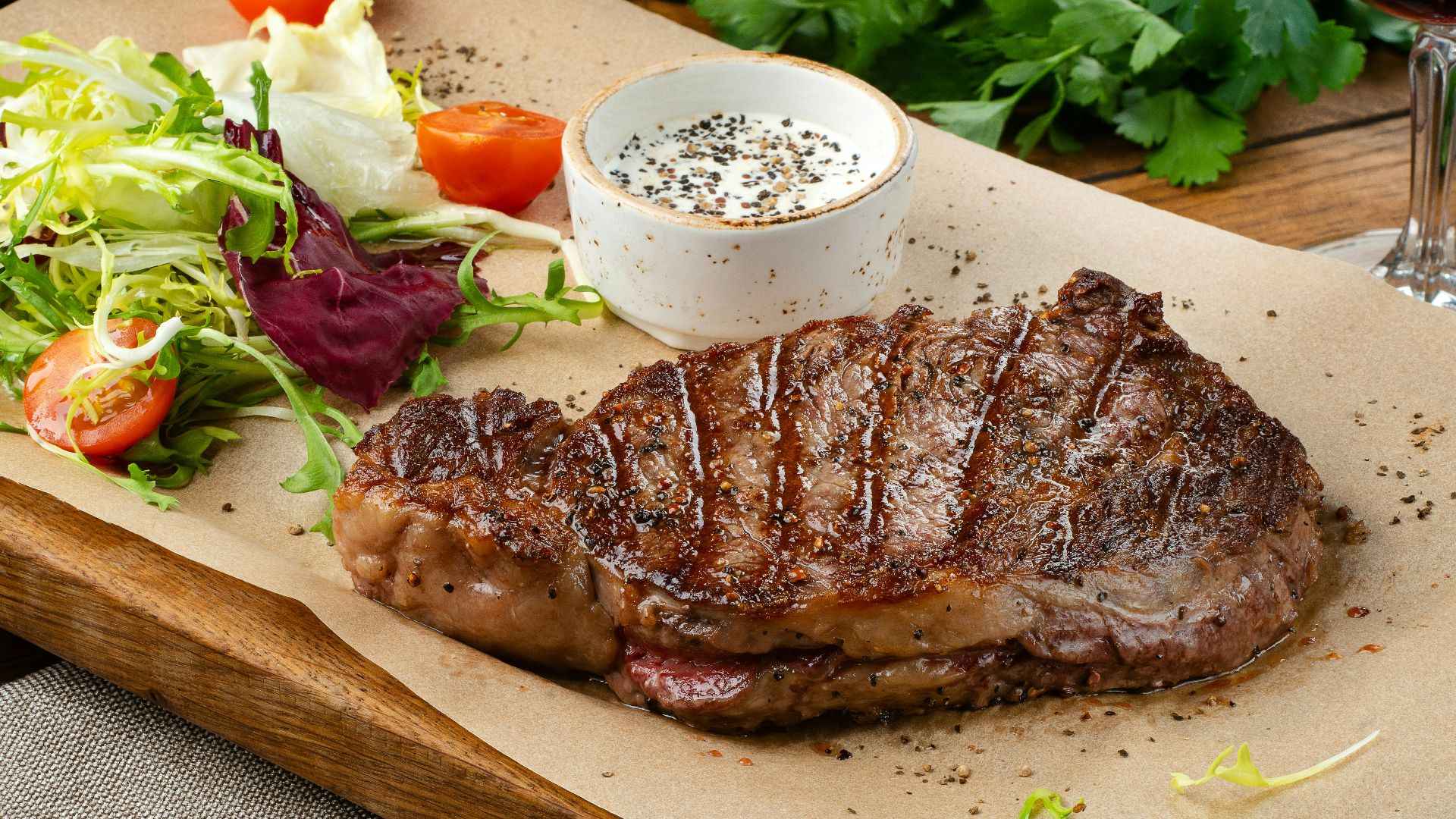 a steak with a side of salad and a glass of wine