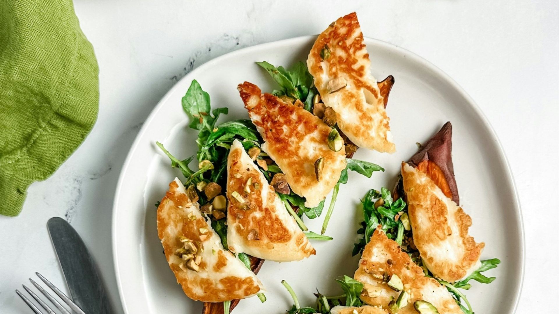 a white plate topped with food next to a knife and fork