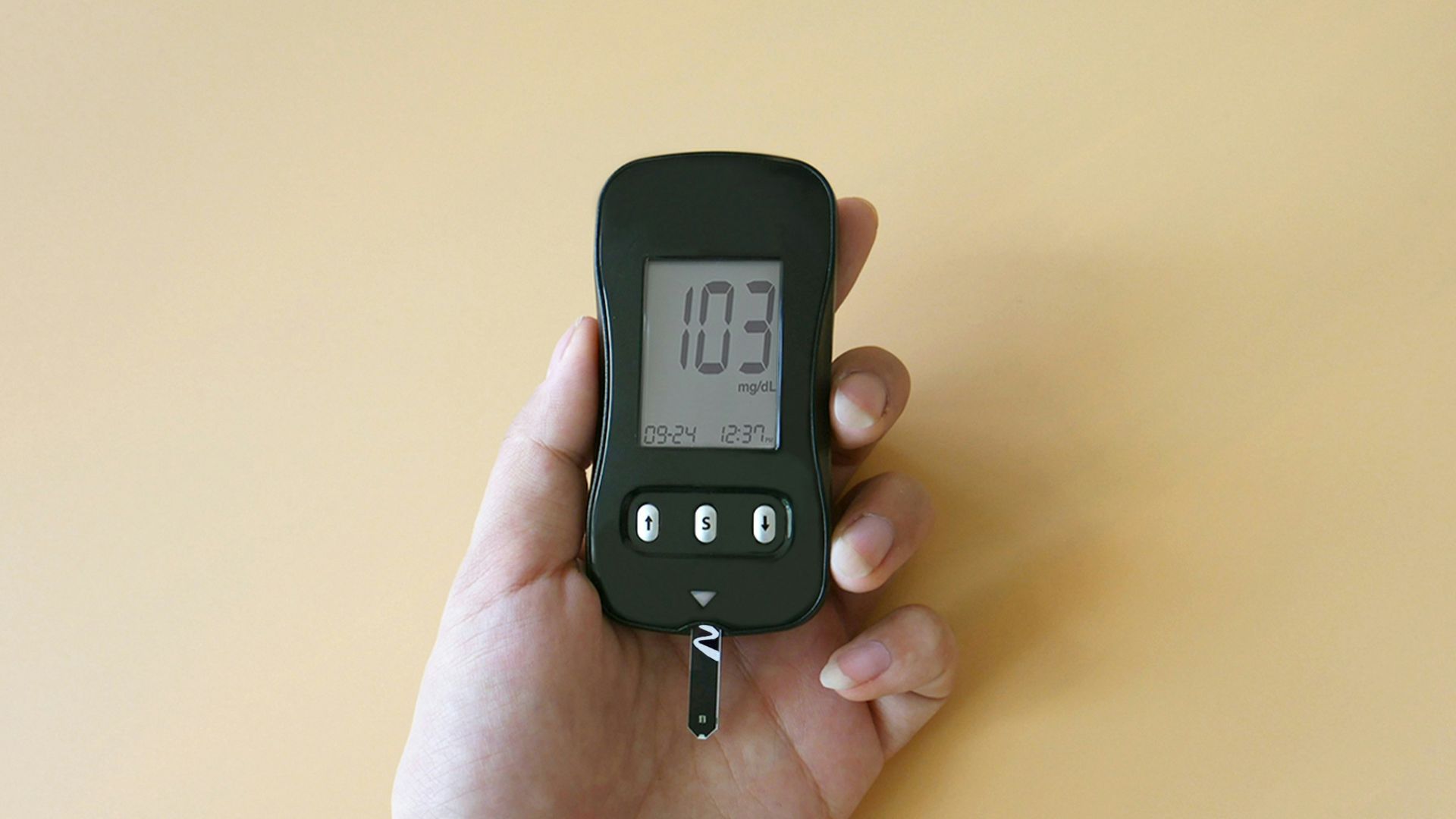 a hand holding a digital thermometer on a yellow background