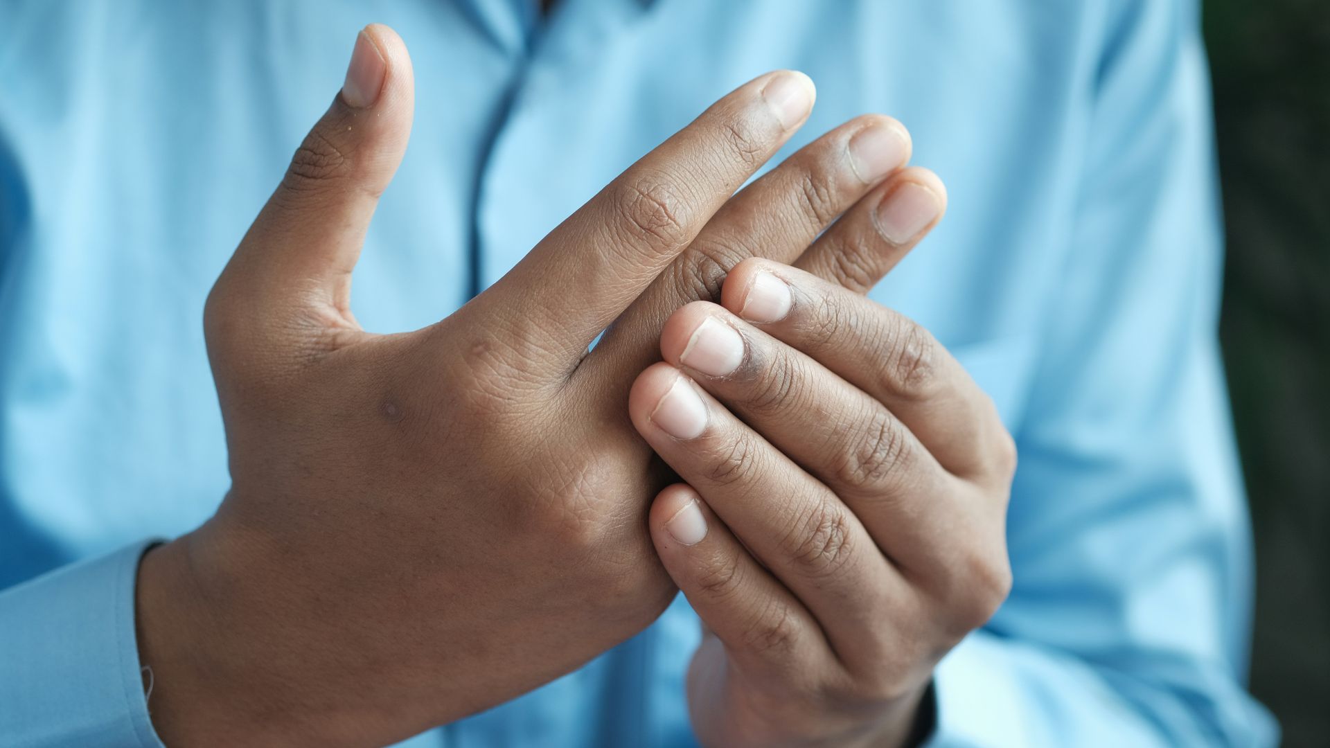 person in blue shirt showing left hand