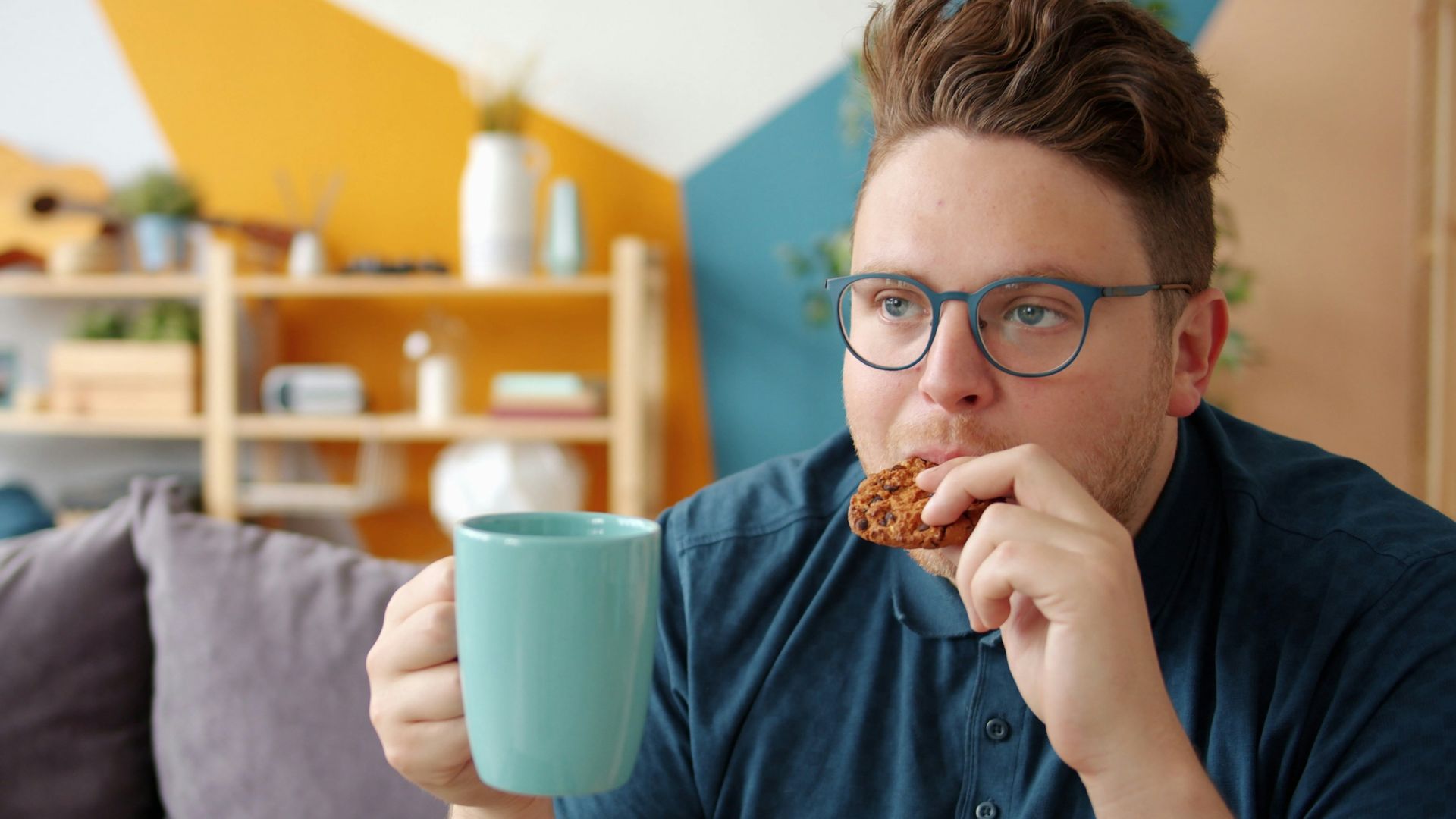 Man eating a cookie and holding a mug