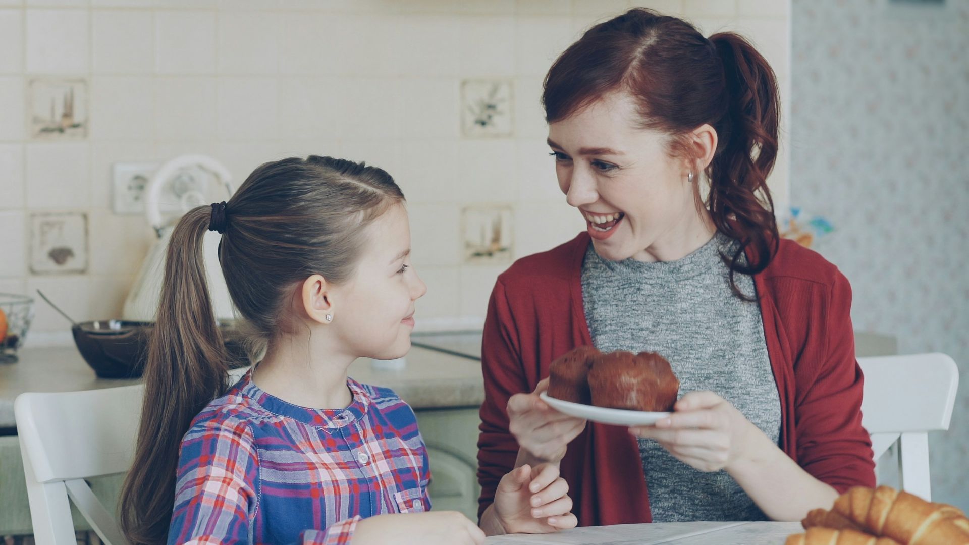 Mother and daughter sharing a treat in the kitchen.