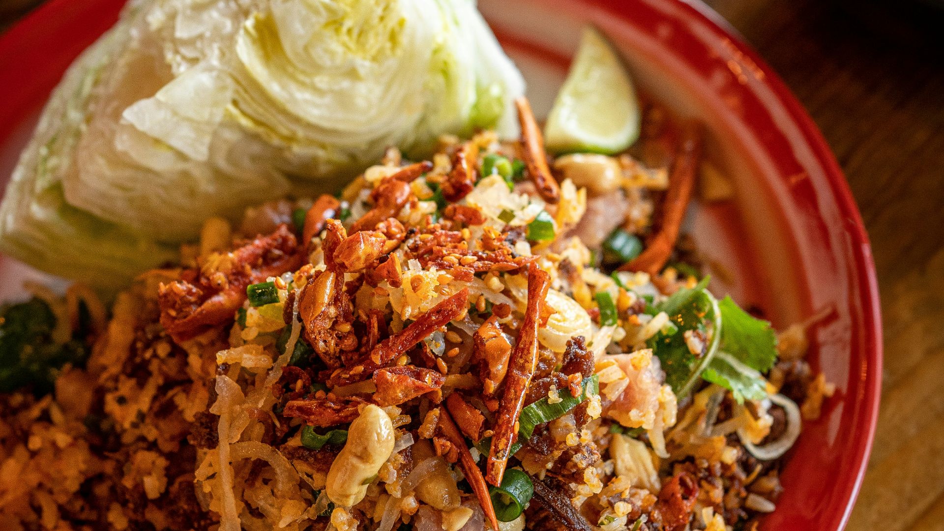 a red plate topped with lots of food on top of a wooden table