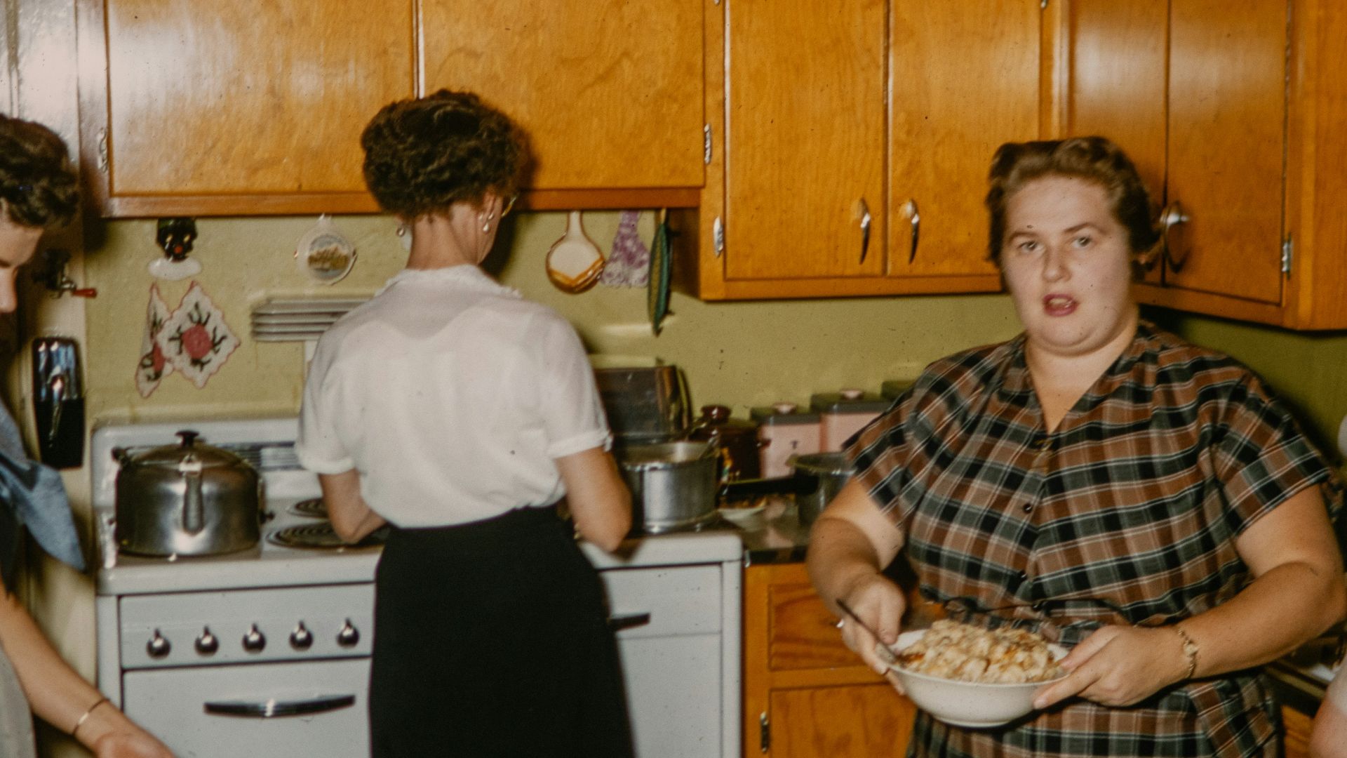 a group of women standing around a kitchen preparing food
