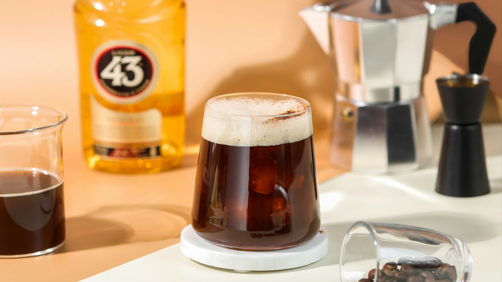 a glass of liquid and a bottle of alcohol on a table