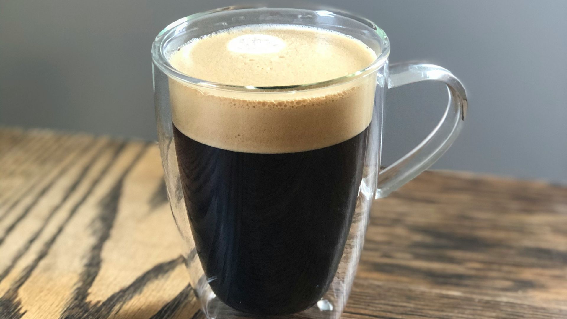 clear glass mug with brown liquid on brown wooden table