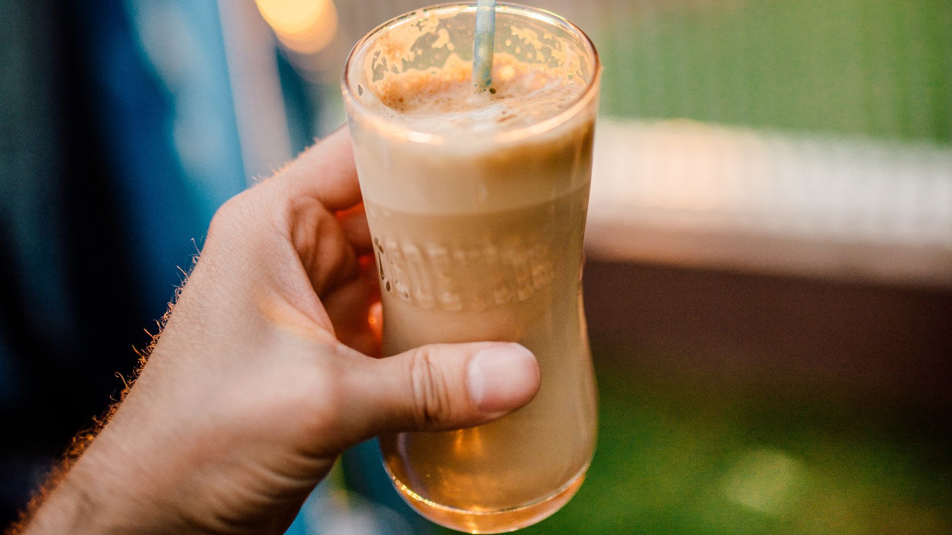 File:A young man holding a glass of iced coffee at home at sundown. Happy hour non-alcoholic beverage.jpg
