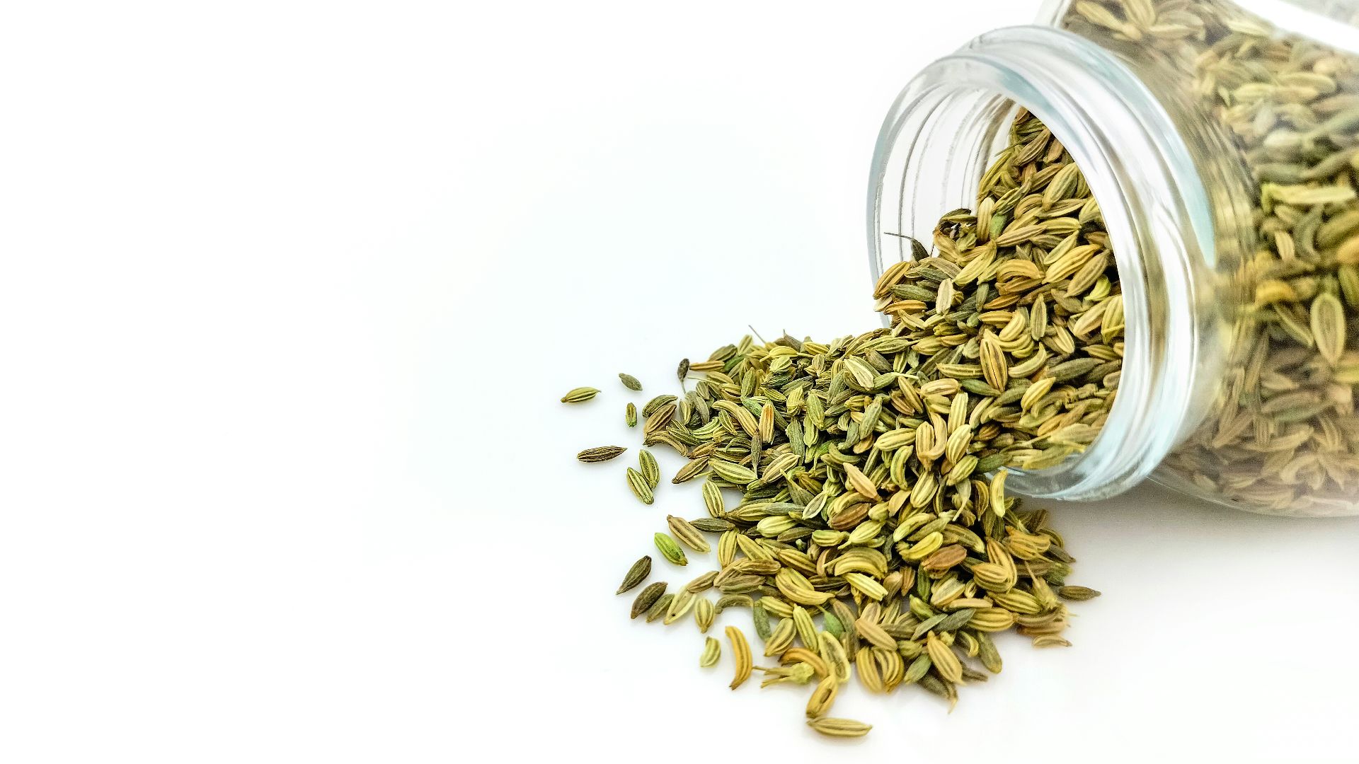 a glass jar filled with seeds on top of a white table