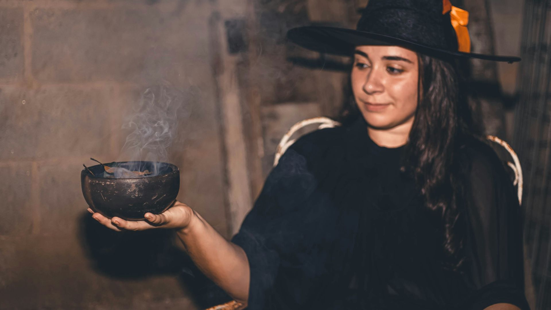 a woman in a witches costume holding a bowl