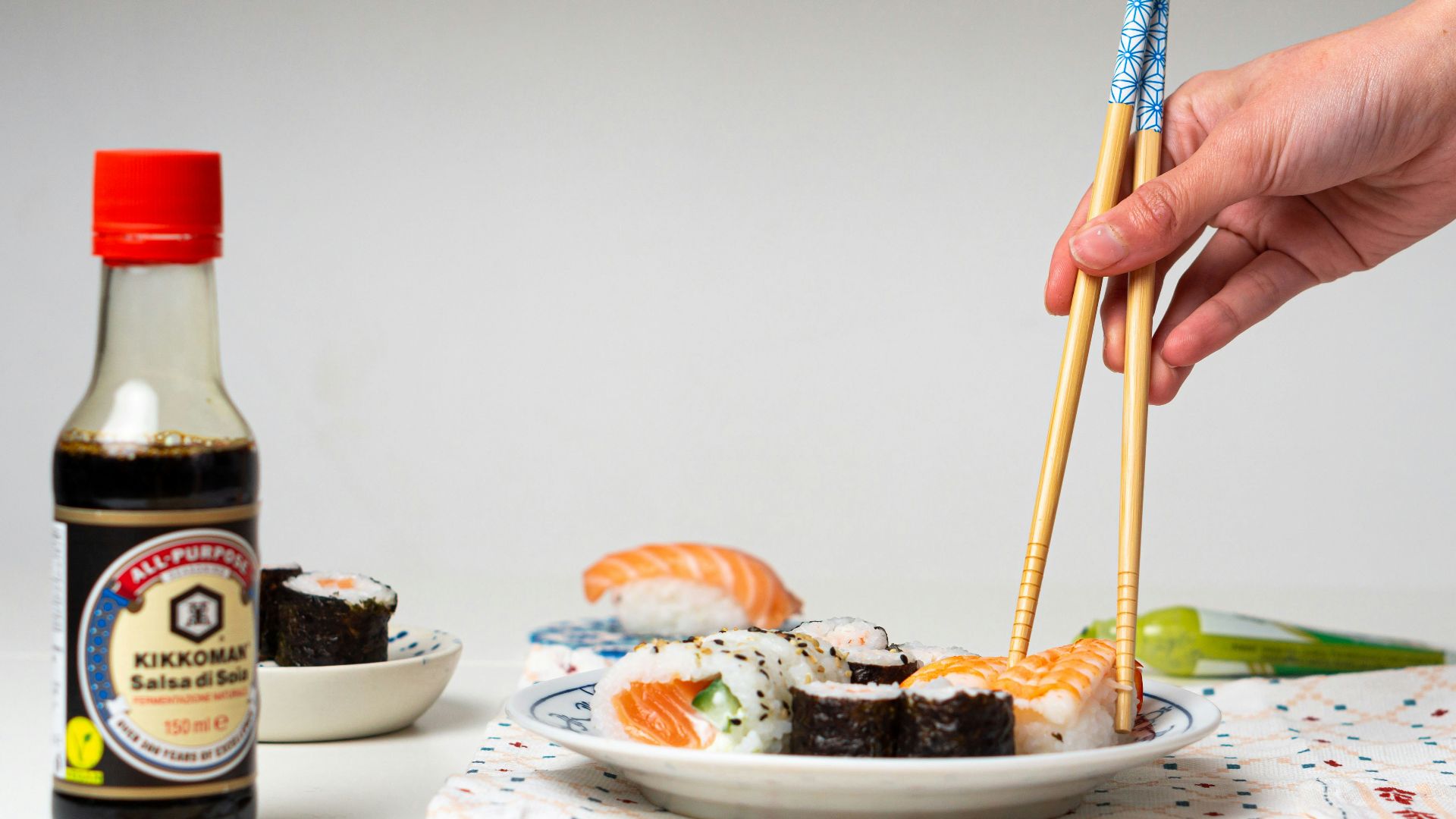 a person holding chopsticks over a plate of sushi
