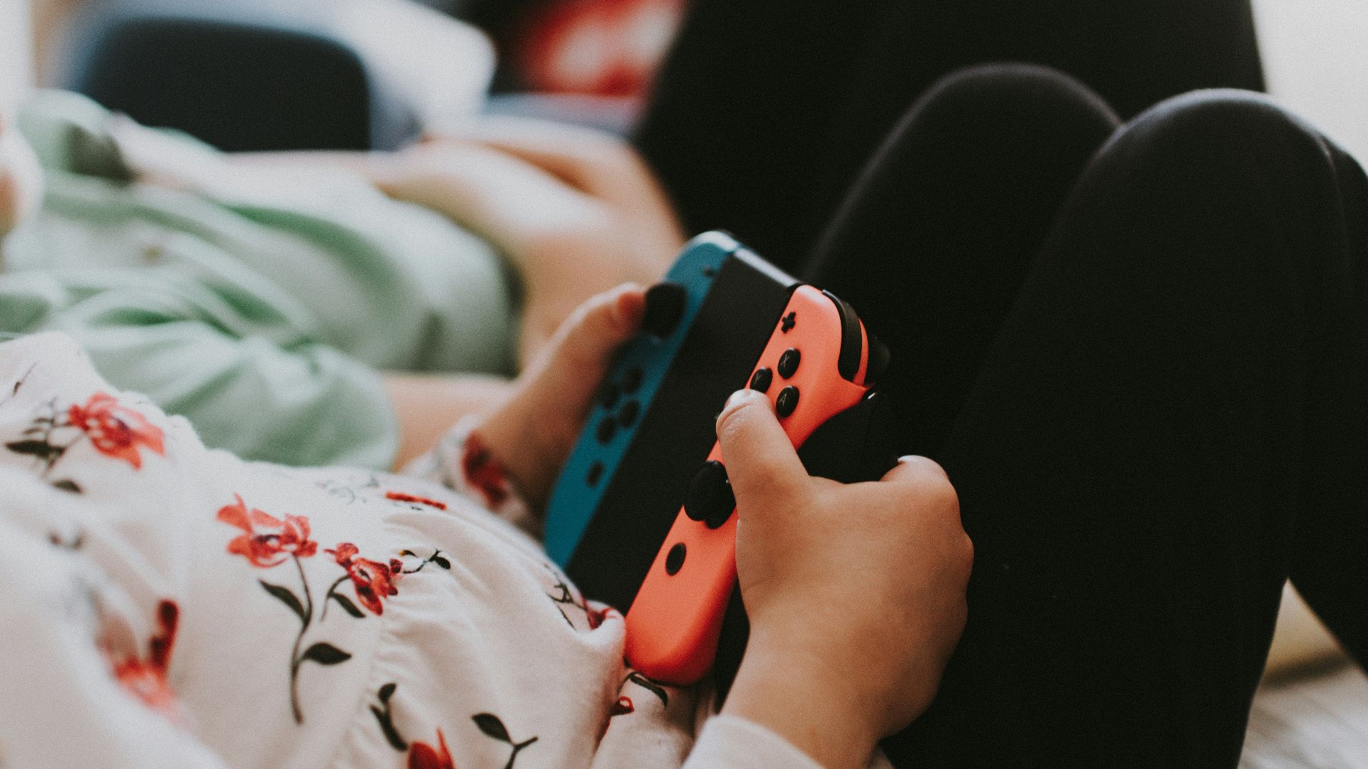 person holding blue and orange Joy Con controller