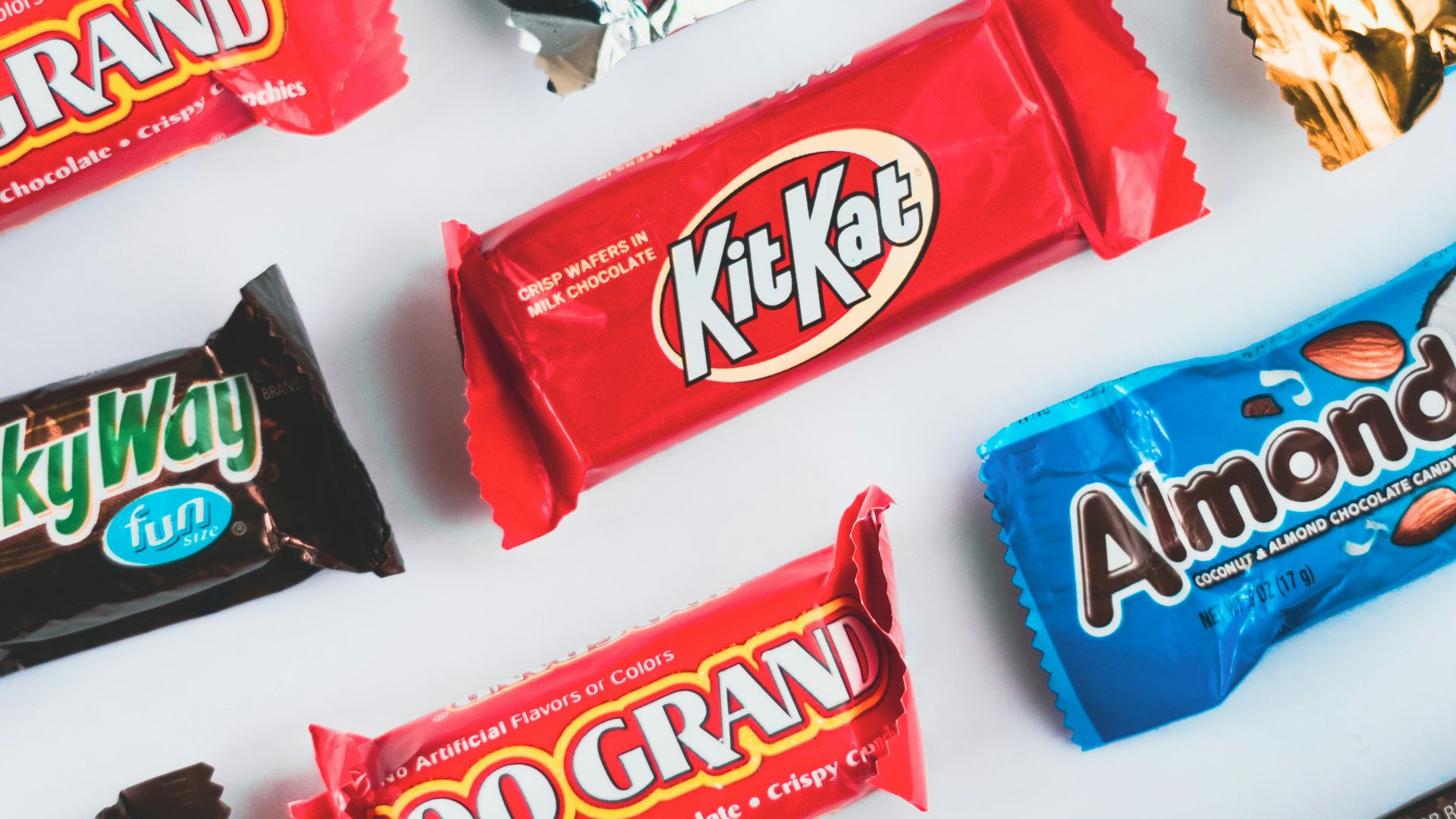 a variety of candy bars lined up on a white surface